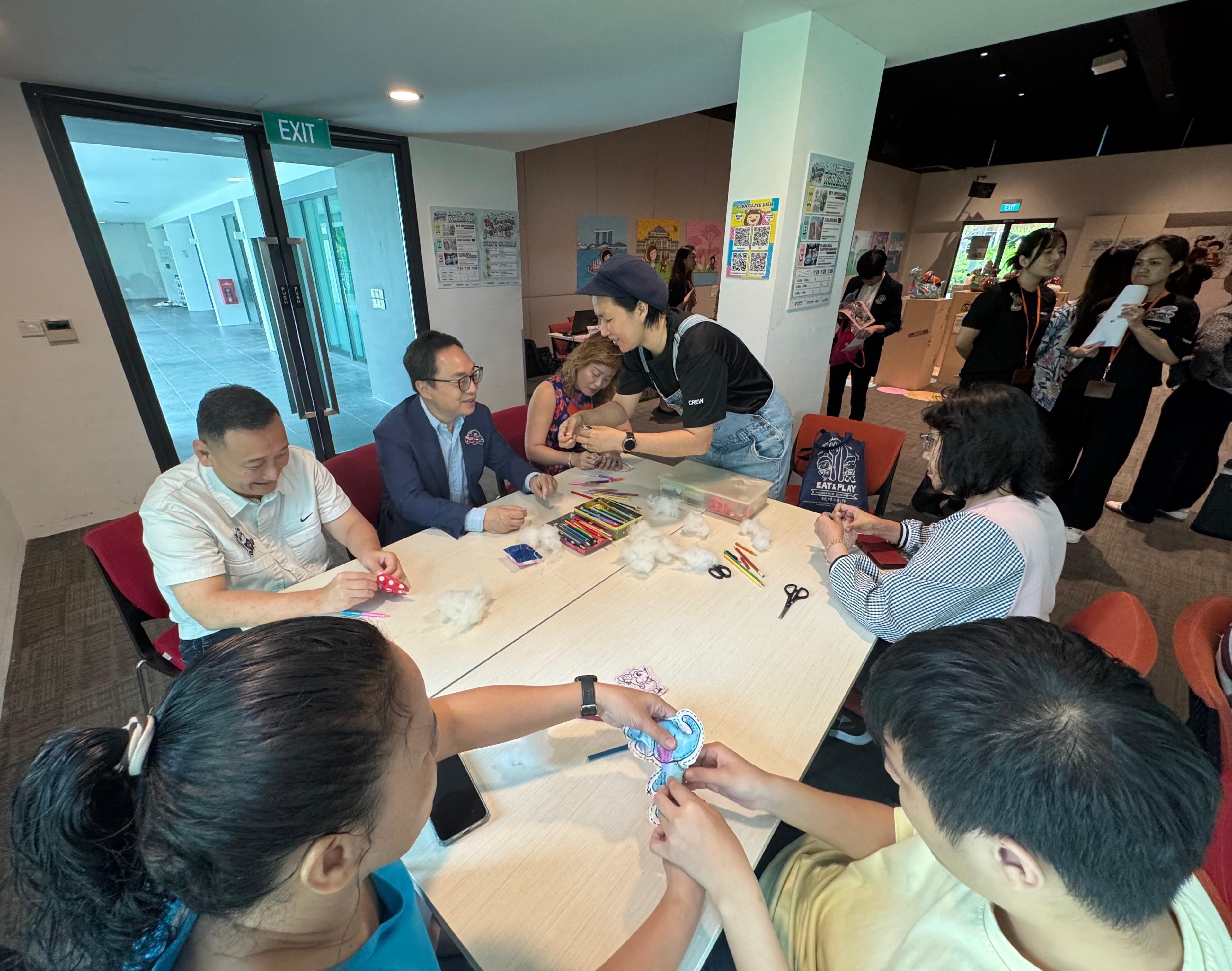 香港駐新加坡經濟貿易辦事處（駐新加坡經貿辦）與香港知名創作品牌Chocolate Rain於今日（十月二十三日）至十月二十六日，共同在新加坡新協立綜合設施舉辦社區藝術展。這場繽紛多彩的展覽歡迎不同藝術愛好者參觀，藉此促進香港與新加坡之間的文化交流。圖示駐新加坡經貿辦處長馮浩然（後排左二）與多個社會服務組織主管親身參與其中一場工作坊，與其他參加者一同體驗升級再造藝術的樂趣，體現展覽所倡導的共融與創意精神。