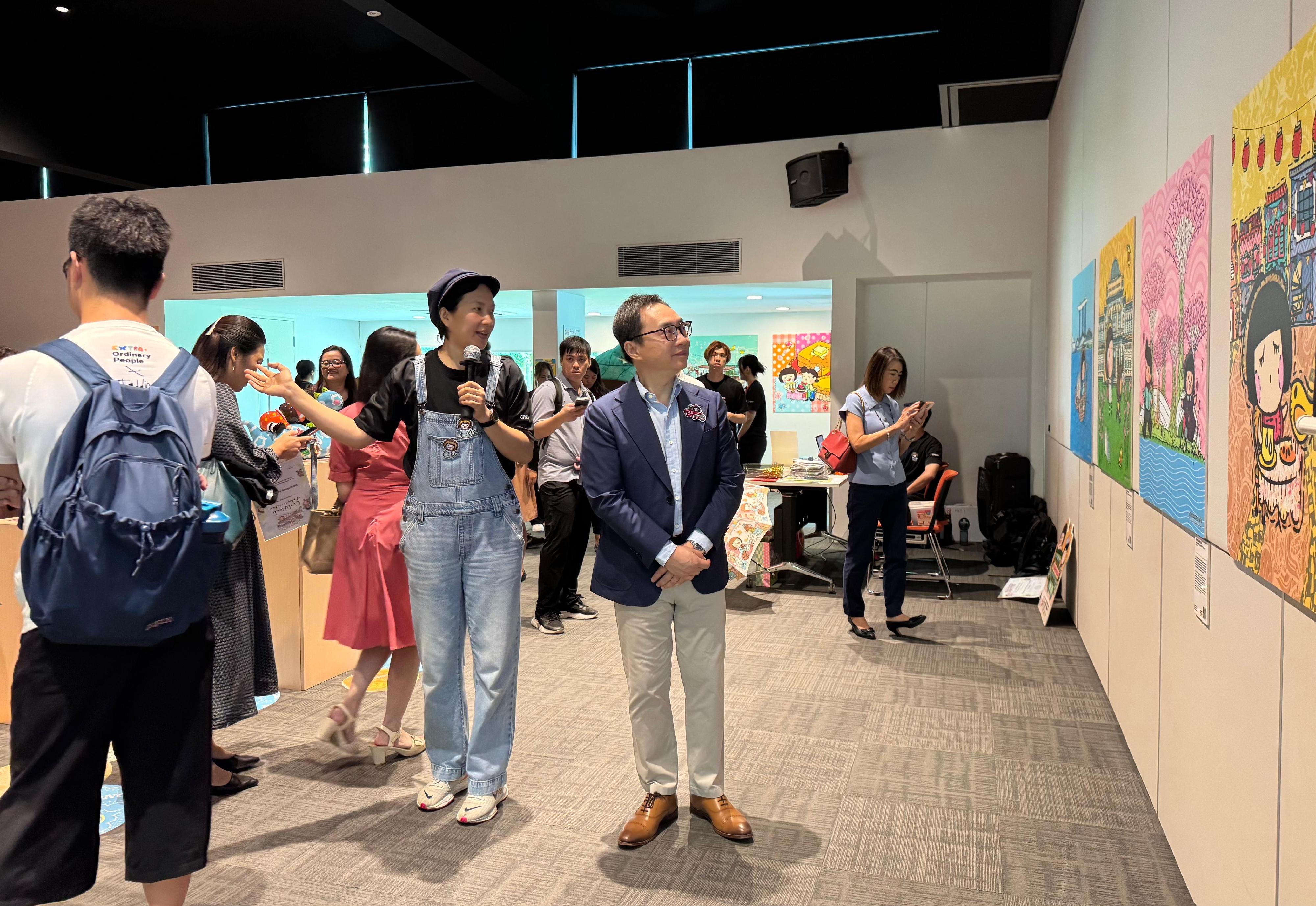 香港駐新加坡經濟貿易辦事處（駐新加坡經貿辦）與香港知名創作品牌Chocolate Rain於今日（十月二十三日）至十月二十六日，共同在新加坡新協立綜合設施舉辦社區藝術展。這場繽紛多彩的展覽歡迎不同藝術愛好者參觀，藉此促進香港與新加坡之間的文化交流。圖示Chocolate Rain創辦人麥雅端（左）向駐新加坡經貿辦處長馮浩然（右）介紹展覽的設計理念。