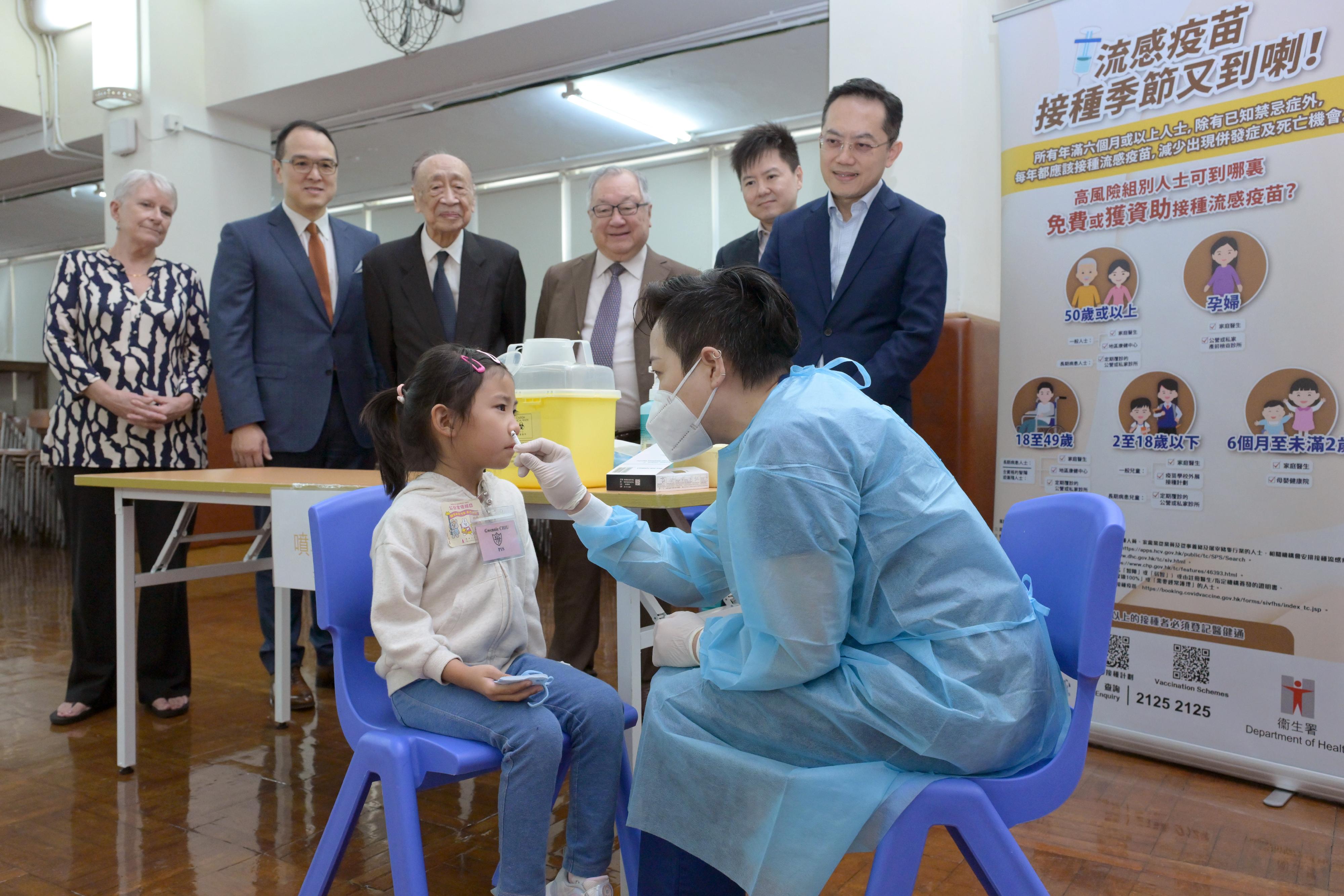 The Director of Health, Dr Ronald Lam, visited Kiangsu & Chekiang Primary School (International Section) in North Point this morning (October 28) to inspect the arrangements for the Seasonal Influenza Vaccination (SIV) School Outreach. He also urged schools to complete their vaccination activities as early as possible to provide convenience for parents. Working together to boost the vaccination rates can help reduce the risk of serious illness and death from seasonal influenza among children. Photo shows Dr Lam (back row, first right) and the Controller of the Centre for Health Protection, Dr Edwin Tsui (back row, second right), accompanied by school representatives, observing a student receiving the live attenuated influenza vaccine (i.e. nasal vaccine).