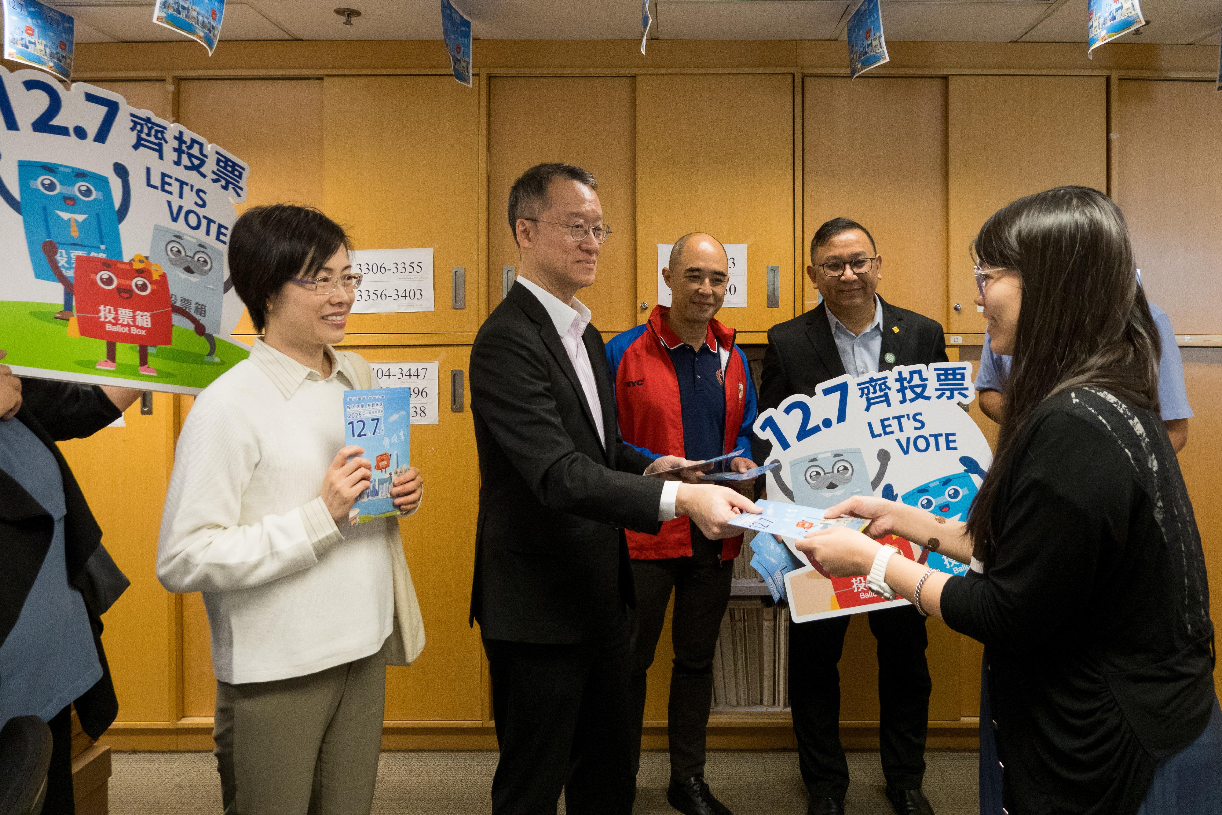 政務司司長陳國基和公務員事務局局長楊何蓓茵今日(十一月十二日)聯同公務員事務局內高層人員,與四個公務員中央評議會職方代表和四個主要跨部門公務員團體代表,一起到金鐘道政府合署多個樓層,呼籲不同部門的同事在立法會選舉齊投票。圖示土地註冊處處長陸嘉健(左二)在土地註冊處的工作間向公務員派發宣傳單張,提醒同事與家人在十二月七日立法會選舉中投票。旁為公務員事務局副秘書長劉思敏(左一)。