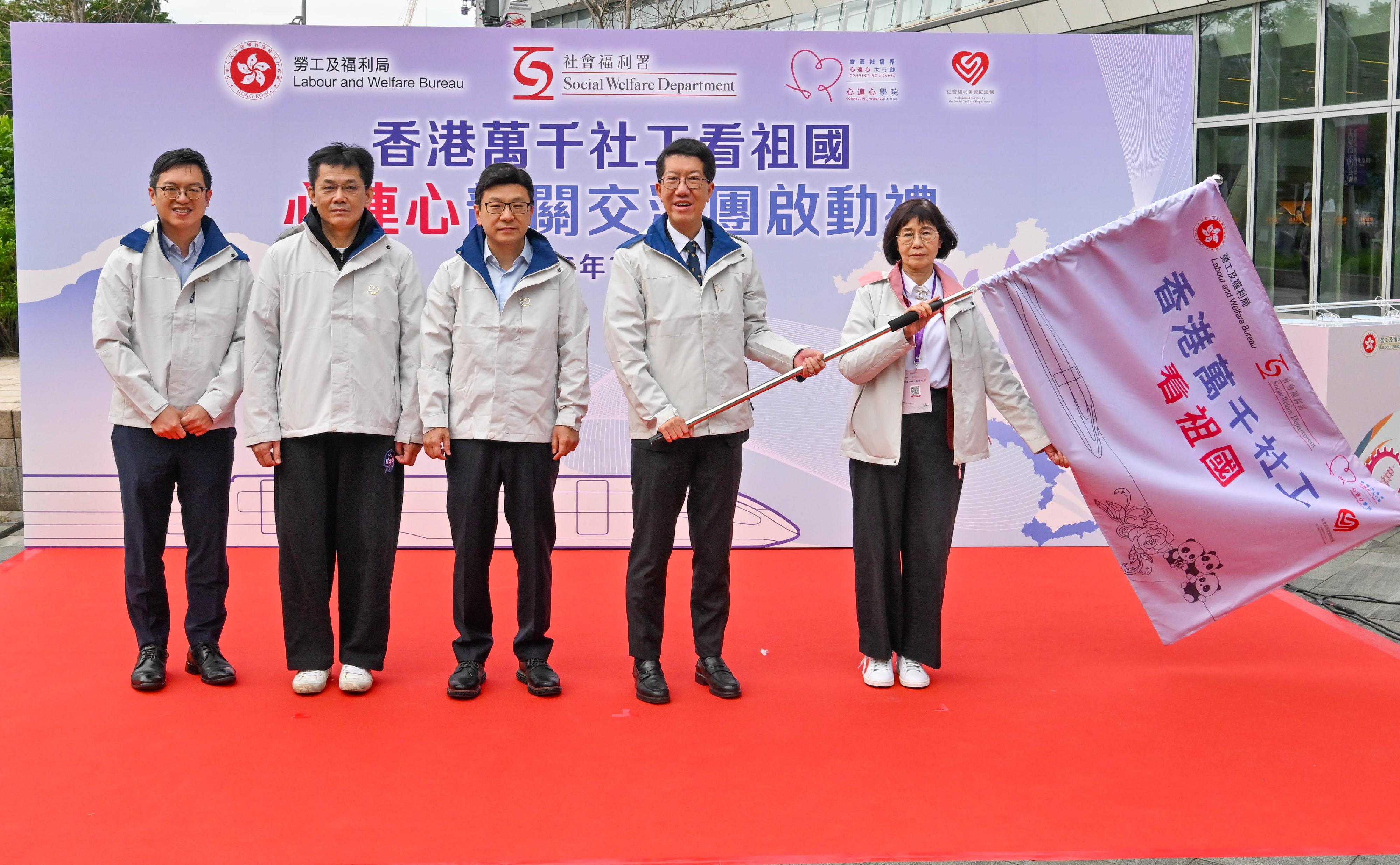 勞工及福利局局長孫玉菡今日(十一月十三日)為香港萬千社工看祖國——「心連心」韶關交流團啟動禮主禮。圖示孫玉菡(中)、中央人民政府駐香港特別行政區聯絡辦公室社會工作部副部長周和博士(左二)及勞工及福利局副局長何啟明(左一)授旗予社會福利署署長杜永恒(右二)及心連心學院院長譚贛蘭教授(右一)。
