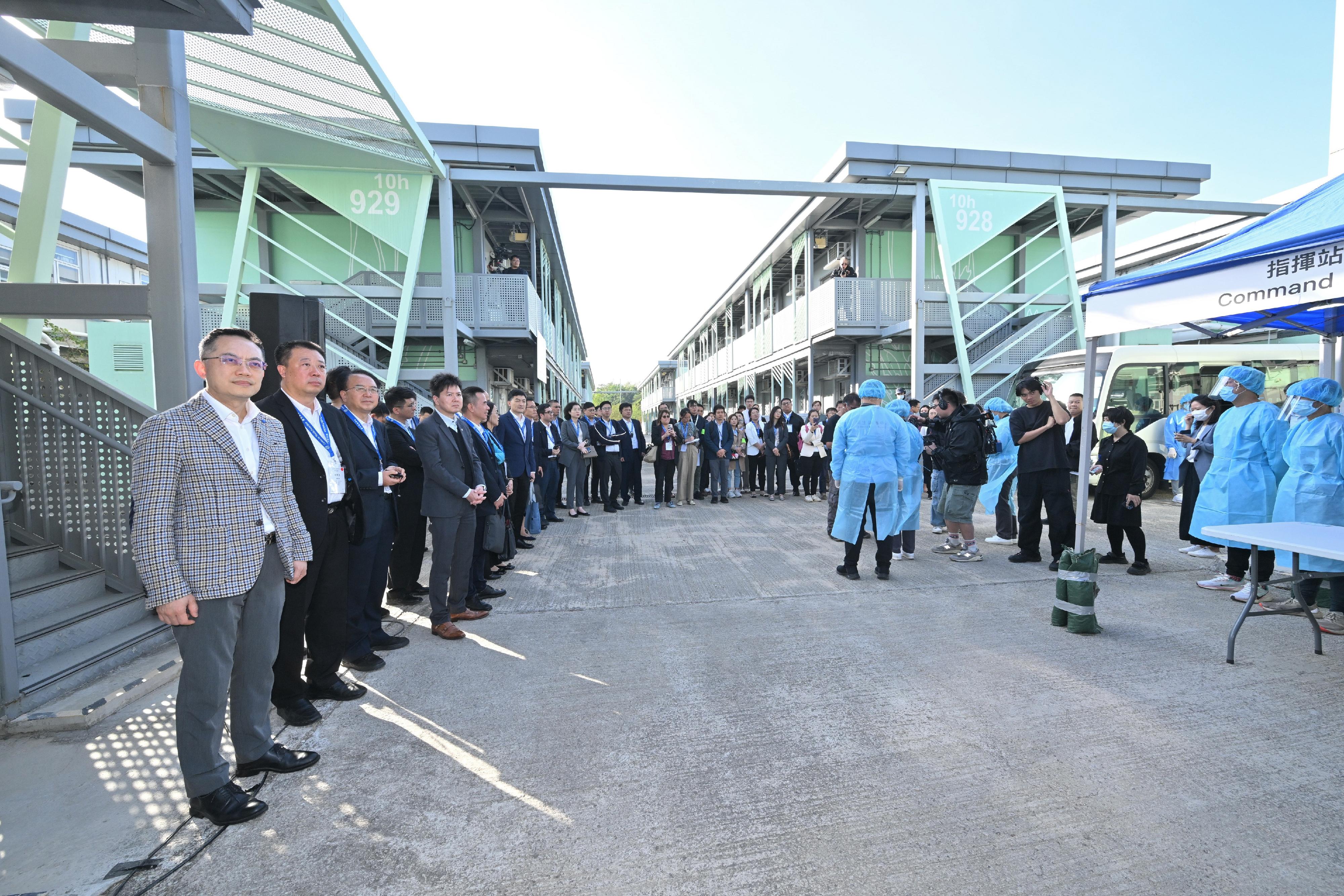 衞生署衞生防護中心（中心）今日（十一月二十五日）聯同多個政府部門舉行代號「紫水晶」的公共衞生演習，以提升中心和相關政府部門處理埃博拉（伊波拉）病個案時的應變能力，並提高持份者對處理突發公共衞生事件的意識。為強化與中國內地及國際交流，此次演習亦邀請了來自國家衞生健康委員會（衞健委）、國家疾病預防控制局（疾控局）、陝西省、湖北省、廣東省、粵港澳大灣區內地城市、澳門特別行政區（特區）和新加坡衞生當局的20多名專家，以觀察員身分出席。圖示中心人員利用流動裝置及電子平台為接觸者進行登記。衞生署署長林文健醫生（左一）、中心總監徐樂堅醫生（左四），以及國家衞健委、國家疾控局、相關內地省市、澳門特區和新加坡衞生部門的專家在旁視察。