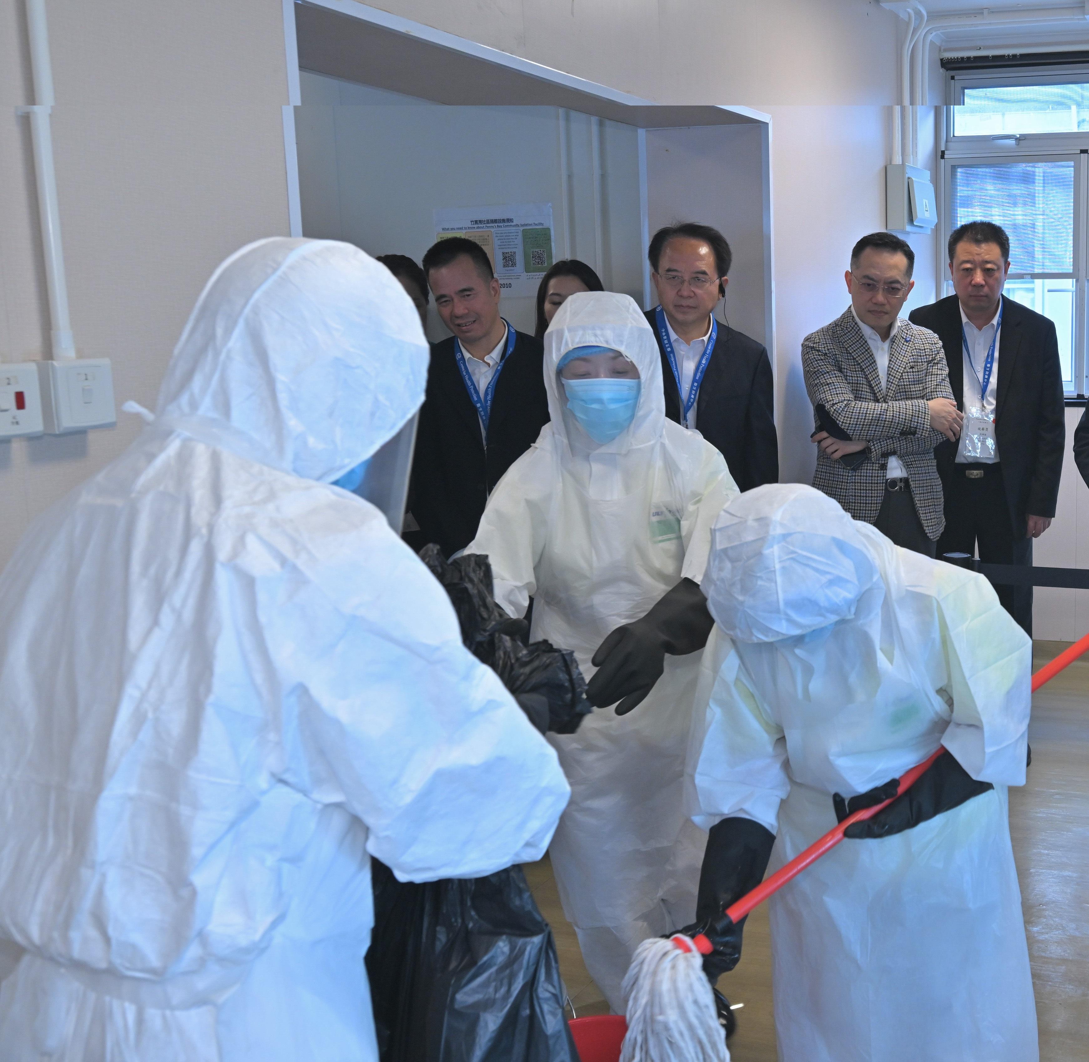 The Centre for Health Protection of the Department of Health (DH), in collaboration with multiple government departments, today (November 25) conducted a public health exercise codenamed "Amethyst" to enhance their response capabilities in dealing with a case of Ebola disease, and to increase awareness among stakeholders about the handling of public health emergencies. To strengthen exchanges with the Chinese Mainland and the international community, over 20 experts from the National Health Commission, the National Disease Control and Prevention Administration, Shaanxi Province, Hubei Province, Guangdong province, Chinese Mainland cities in the Guangdong-Hong Kong-Macao Greater Bay Area, the Macao Special Administrative Region and Singapore health authorities were invited to attend as observers. Photo shows officers from the Food and Environmental Hygiene Department carrying out cleaning and disinfection procedures. The Director of Health, Dr Ronald Lam (back row, second right), and a number of observers are at the scene.