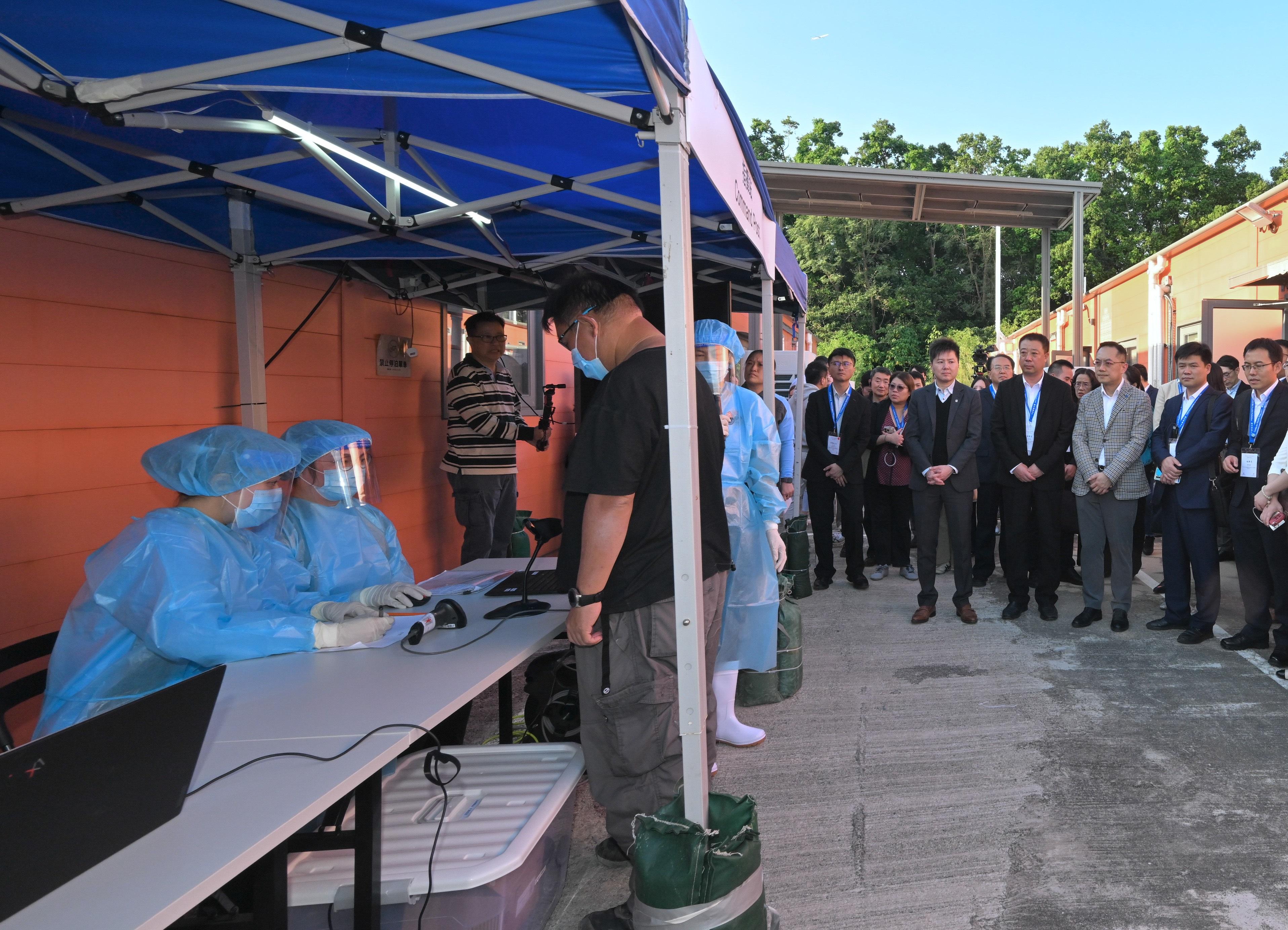 The Centre for Health Protection of the Department of Health (DH), in collaboration with multiple government departments, today (November 25) conducted a public health exercise codenamed "Amethyst" to enhance their response capabilities in dealing with a case of Ebola disease, and to increase awareness among stakeholders about the handling of public health emergencies. To strengthen exchanges with the Chinese Mainland and the international community, over 20 experts from the National Health Commission, the National Disease Control and Prevention Administration, Shaanxi Province, Hubei Province, Guangdong province, Chinese Mainland cities in the Guangdong-Hong Kong-Macao Greater Bay Area, the Macao Special Administrative Region and Singapore health authorities were invited to attend as observers. Photo shows officers from the Civil Aid Service registering the close contacts at the quarantine facilities. The Director of Health, Dr Ronald Lam (third right), and a number of observers are at the scene.