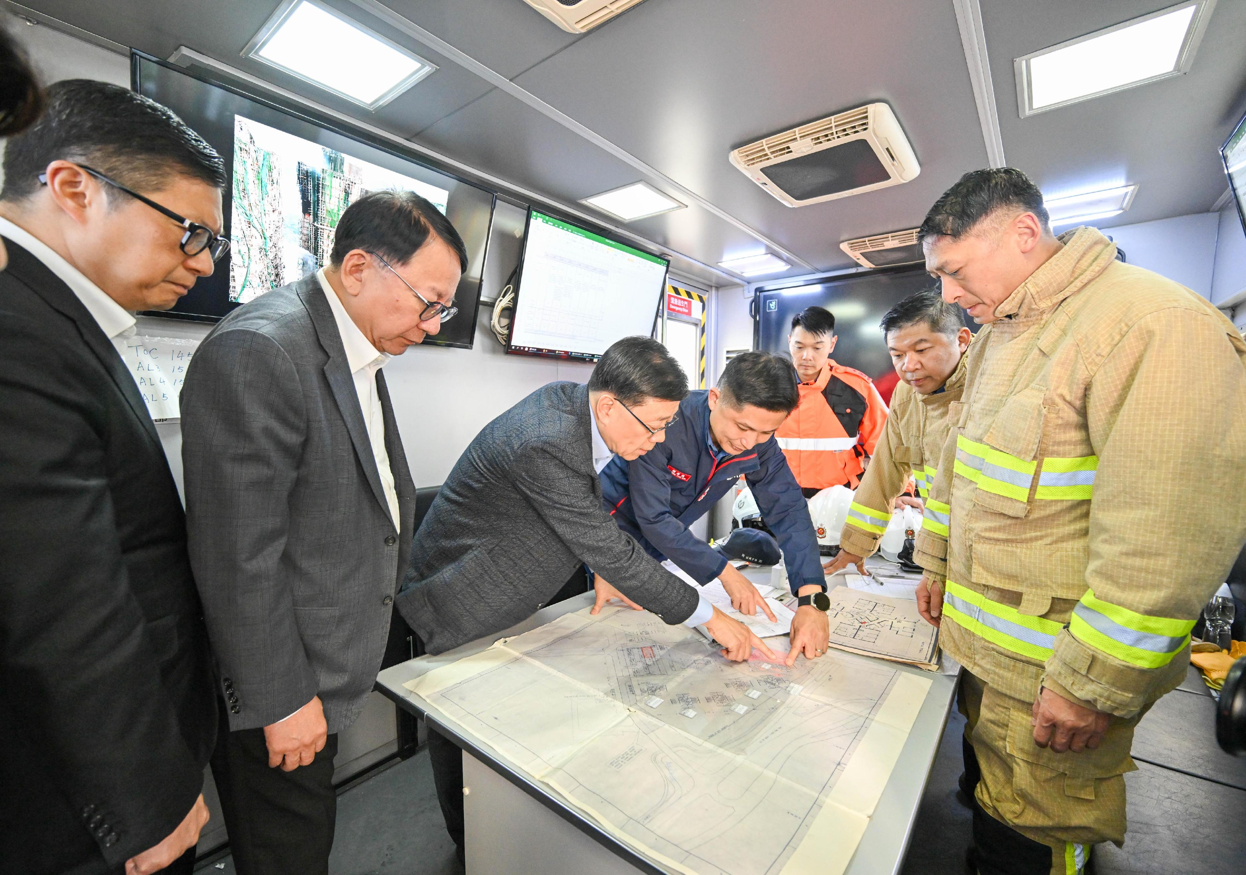 The Chief Executive, Mr John Lee, went to Wang Fuk Court in Tai Po this afternoon (November 27) to inspect the fire scene. Photo shows Mr Lee (third left), the Chief Secretary for Administration, Mr Chan Kwok-ki (second left) and the Secretary for Security, Mr Tang Ping-keung (first left) were briefed on the firefighting operations by the Director of Fire Services, Mr Andy Yeung (fourth right), in the Mobile Command Unit.