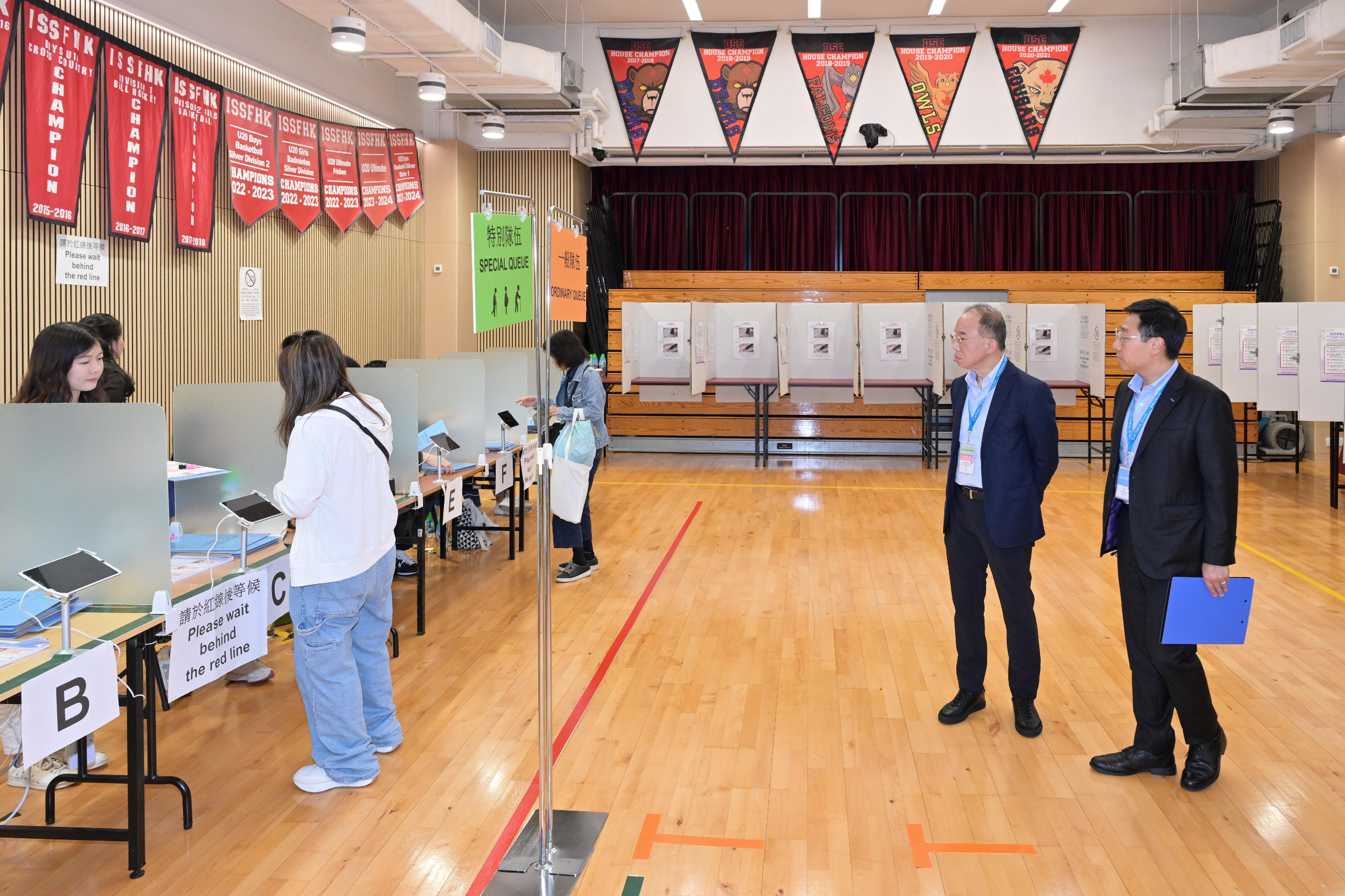 政制及内地事务局局长曾国卫（右二）今日（十二月七日）在鰂鱼涌巡视二○二五年立法会换届选举位于德思齐加拿大国际学校的一般投票站。