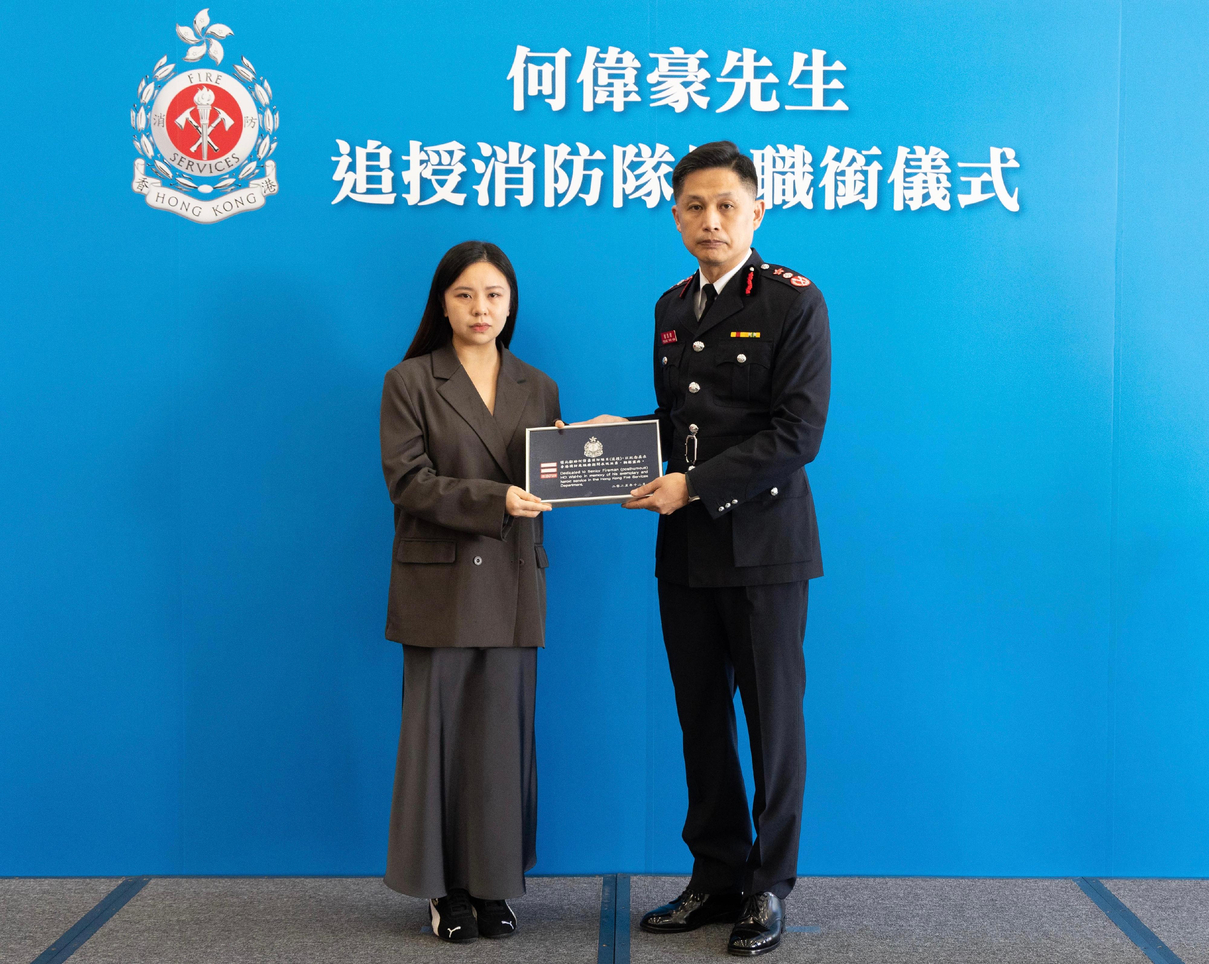 消防处今日（十二月十一日）向已故属员何伟豪追授消防队目荣誉职衔，以表扬他在执行灭火救援工作期间堪称典范的服务及无私的精神。图示消防处处长杨恩健（右）颁授消防队目阶级章刺绣，由何伟豪家人代表接受。