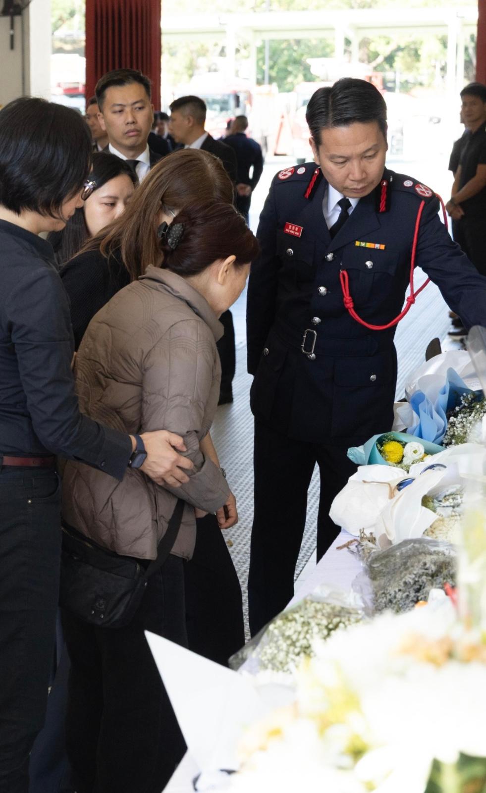 消防处今日（十二月十一日）向已故属员何伟豪追授消防队目荣誉职衔，以表扬他在执行灭火救援工作期间堪称典范的服务及无私的精神。图示消防处助理处长（新界北）邓荣华（右一）与何伟豪家属观看市民致送的鲜花和心意卡。