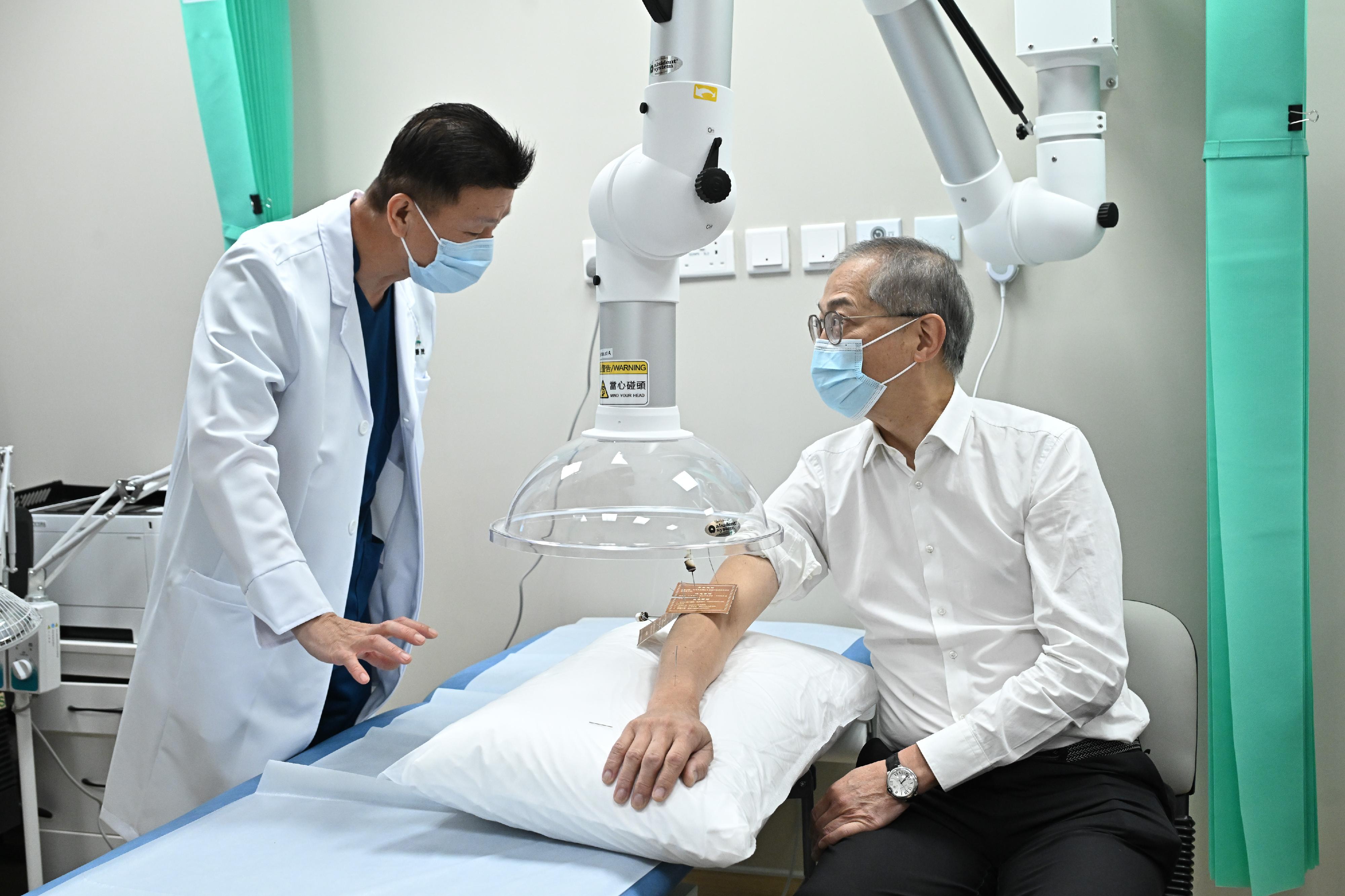 The Chinese Medicine Hospital of Hong Kong commenced operations in phases starting today (December 11). Photo shows the Secretary for Health, Professor Lo Chung-mau (right), undergoing a moxibustion treatment at the hospital today.