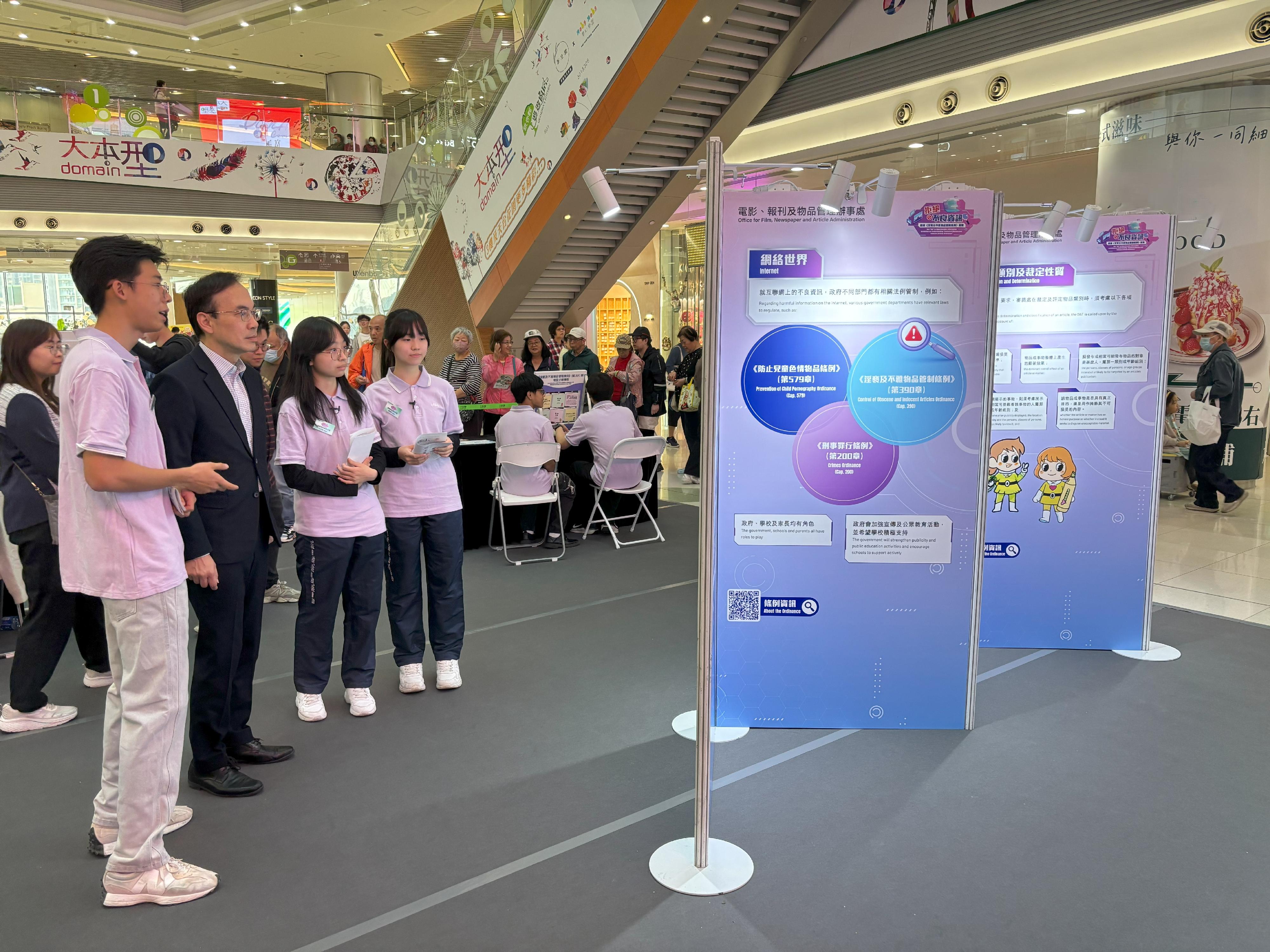 The Office for Film, Newspaper and Article Administration is holding a roving exhibition themed "Saying NO to Objectionable Information" at Domain Mall in Yau Tong for three consecutive days starting from today (December 12) to enhance the public's understanding of the Control of Obscene and Indecent Articles Ordinance and promote healthy Internet use. Photo shows the Director of Film, Newspaper and Article Administration, Mr Chaucer Leung (second left), being briefed on the exhibition panels by the Healthy Information Student Ambassadors at the exhibition.