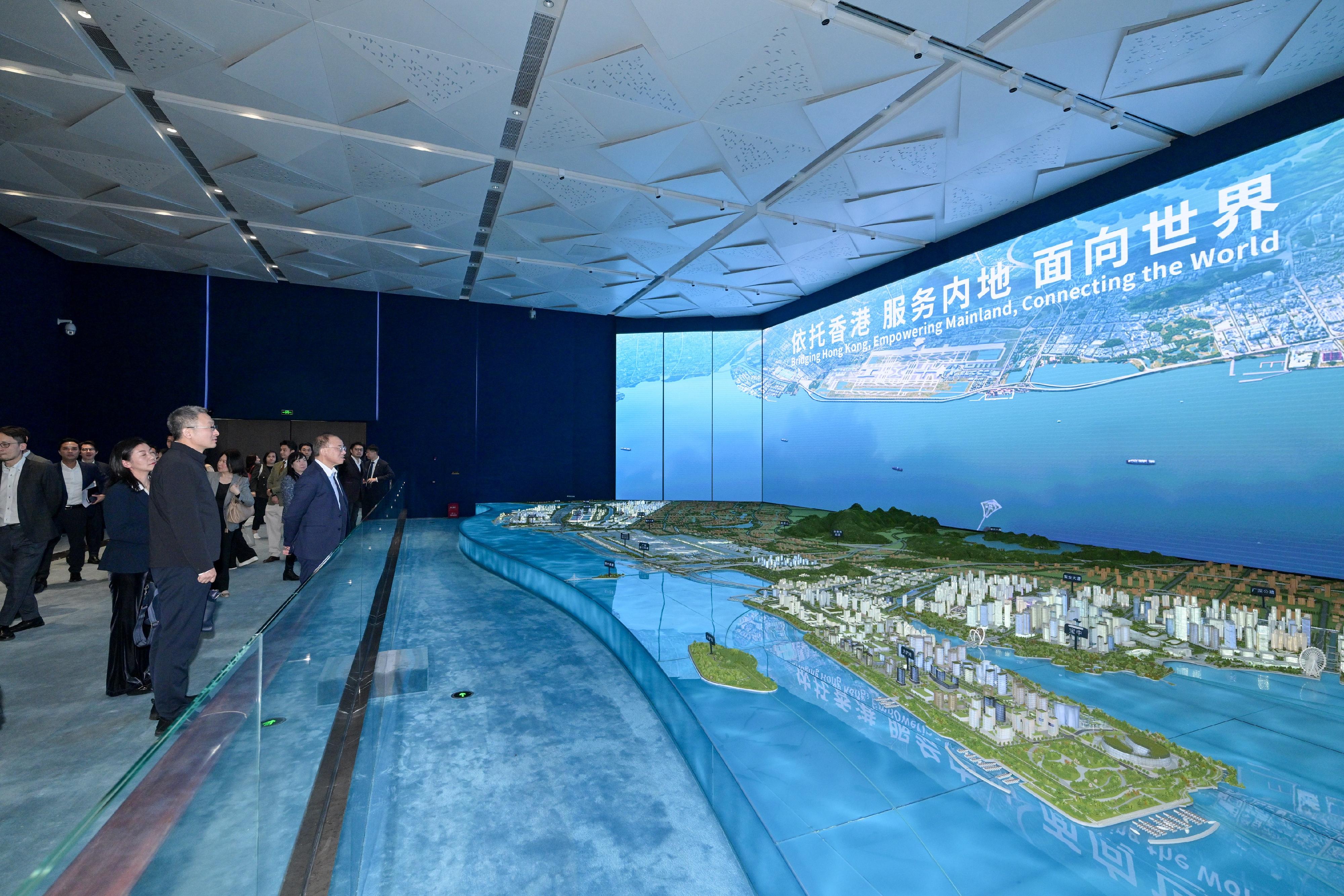 The Secretary for Constitutional and Mainland Affairs, Mr Erick Tsang Kwok-wai, and member of the Standing Committee of the CPC Shenzhen Municipal Committee and Director General of the Authority of Qianhai Shenzhen-Hong Kong Modern Service Industry Co-operation Zone of Shenzhen Municipality, Mr Wang Shourui, leading representatives of relevant bureaux and departments of the Hong Kong Special Administrative Region Government and the delegation of the Shenzhen Municipal Government respectively, held the second meeting of the Task Force on the Development of the Qianhai Shenzhen-Hong Kong Modern Service Industry Co-operation Zone in Shenzhen today (December 18). Photo shows Mr Tsang (front row, second left) and other members of the delegation being briefed on the latest developments of Qianhai at the Qianhai Exhibition Hall after the meeting.