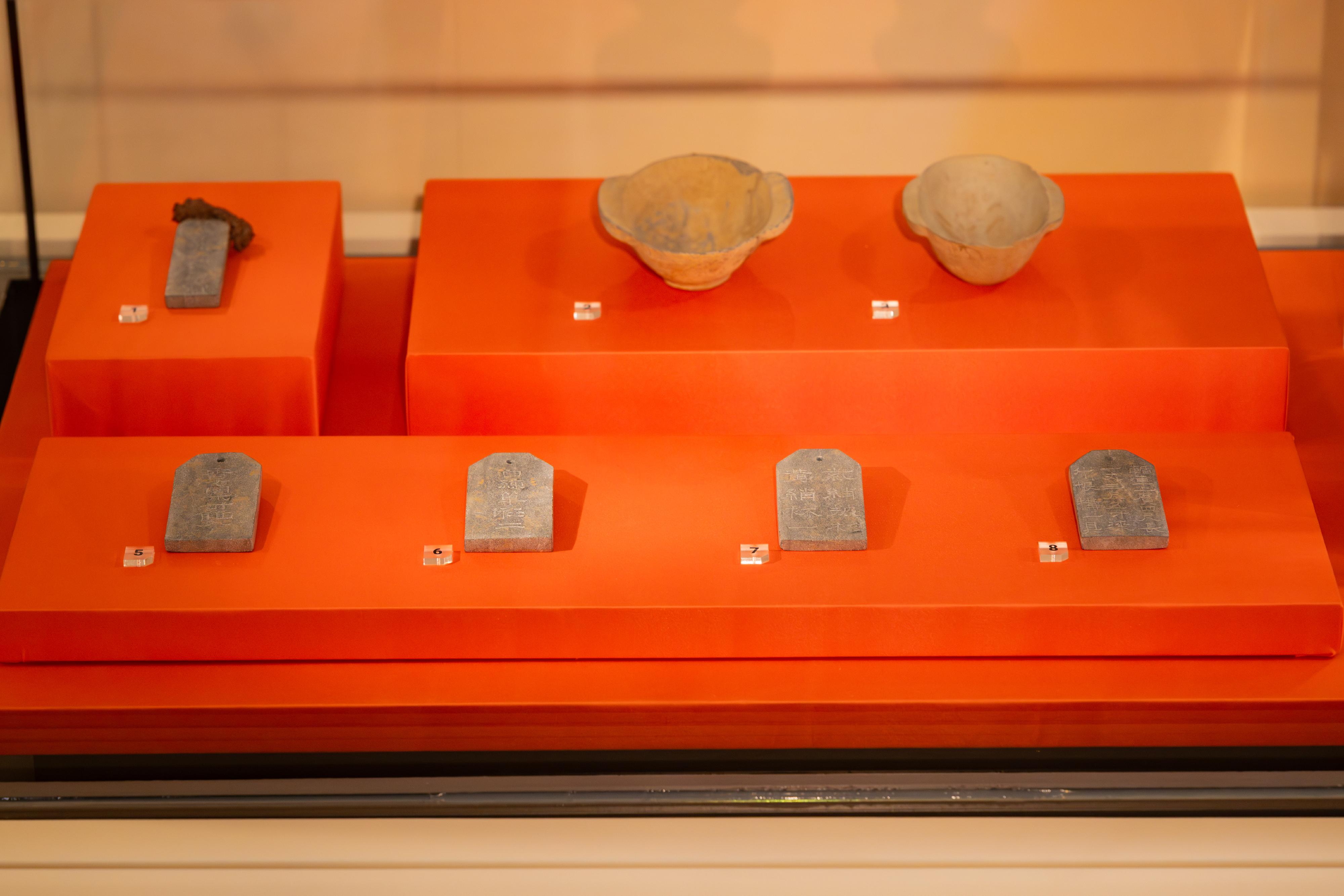 The Chinese Culture Promotion Office of the Leisure and Cultural Services Department will hold the "Archaeology of Cao Cao" Exhibition at the Lobby, 1/F, Hong Kong Museum of History, from tomorrow (December 31) to February 23, 2026. Photo shows a stone tablet with inscription reading "large halberd often used by King Wu of Wei to kill tigers" (replica) on the left of the back row; pottery drinking cups from the Eastern Han dynasty (erbei) (replica) at the centre and right of the back row; and stone tablets inscribed with the names and quantities of burial items (replica) on the front row.