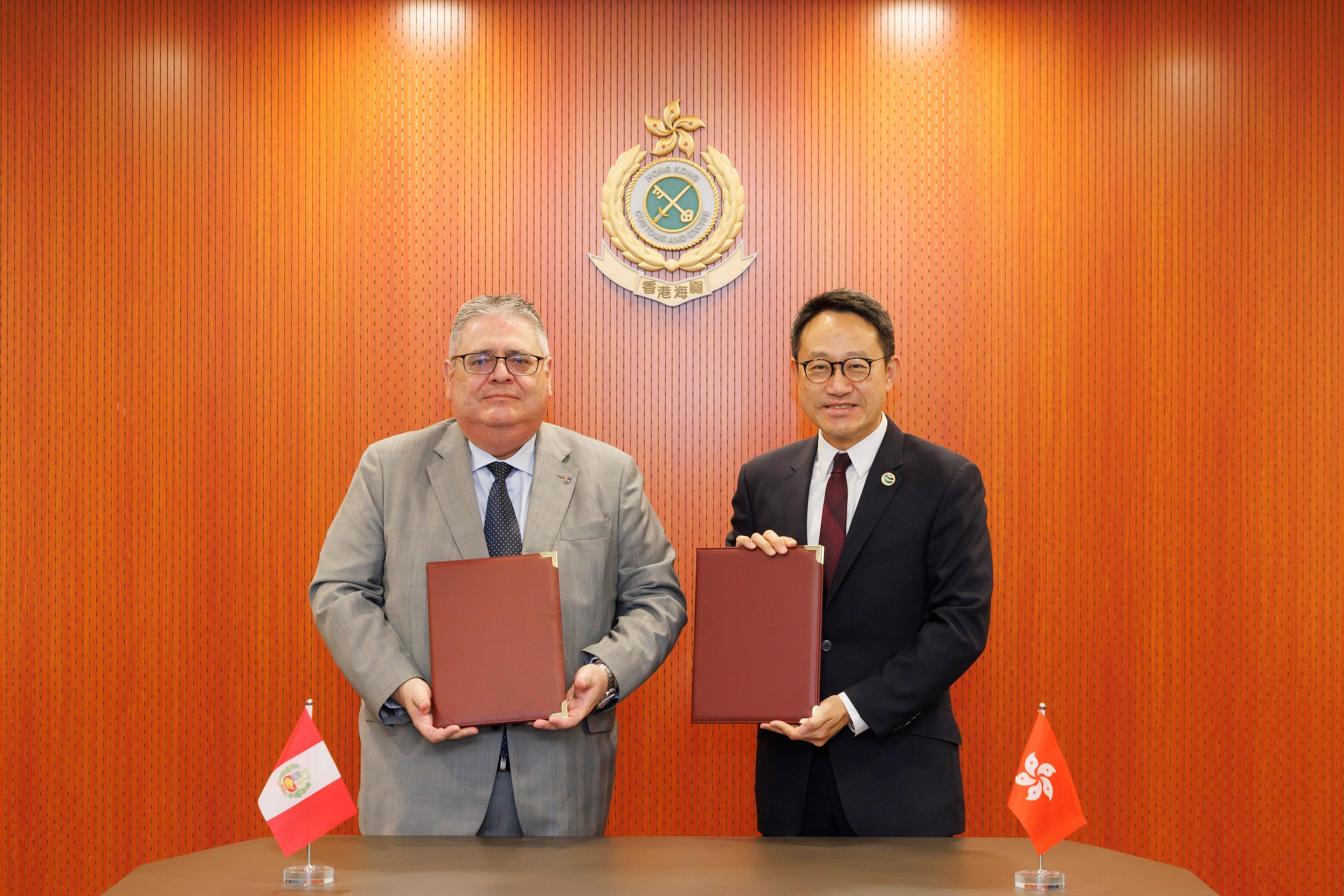 The Commissioner of Customs and Excise, Mr Chan Tsz-tat, concluded the Mutual Recognition Arrangement on Authorized Economic Operator Programme with the National Superintendence of Customs and Tax Administration of Peru in hybrid mode at the Customs Headquarters Building today (December 30). Photo shows Mr Chan (right) exchanging the signed text with the Consul-General of Peru, Mr Enrique Carlos Cardenas Arestegui (left).