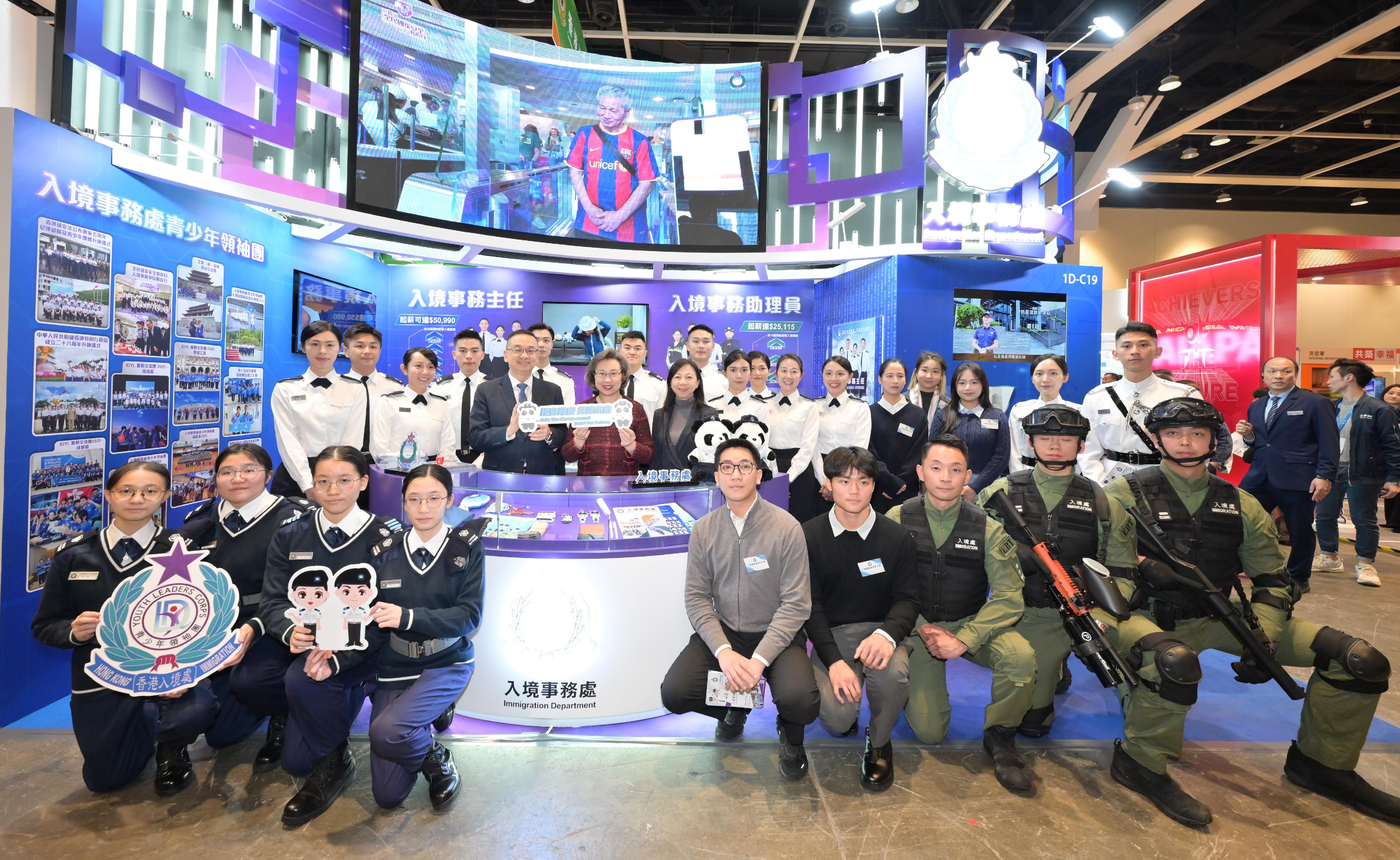 公務員事務局局長楊何蓓茵今日（一月二十二日）參觀多個決策局和部門設於教育及職業博覽2026的展區，並鼓勵學生和青年認識不同政府部門的多元工作和提供的就業機會，積極考慮日後投身政府，共建香港的未來。圖示楊何蓓茵（第二排左四）和公務員事務局常任秘書長林雪麗（第二排左五）在入境事務處的展區與入境事務處處長郭俊峯（第二排左三）及處方人員合照。