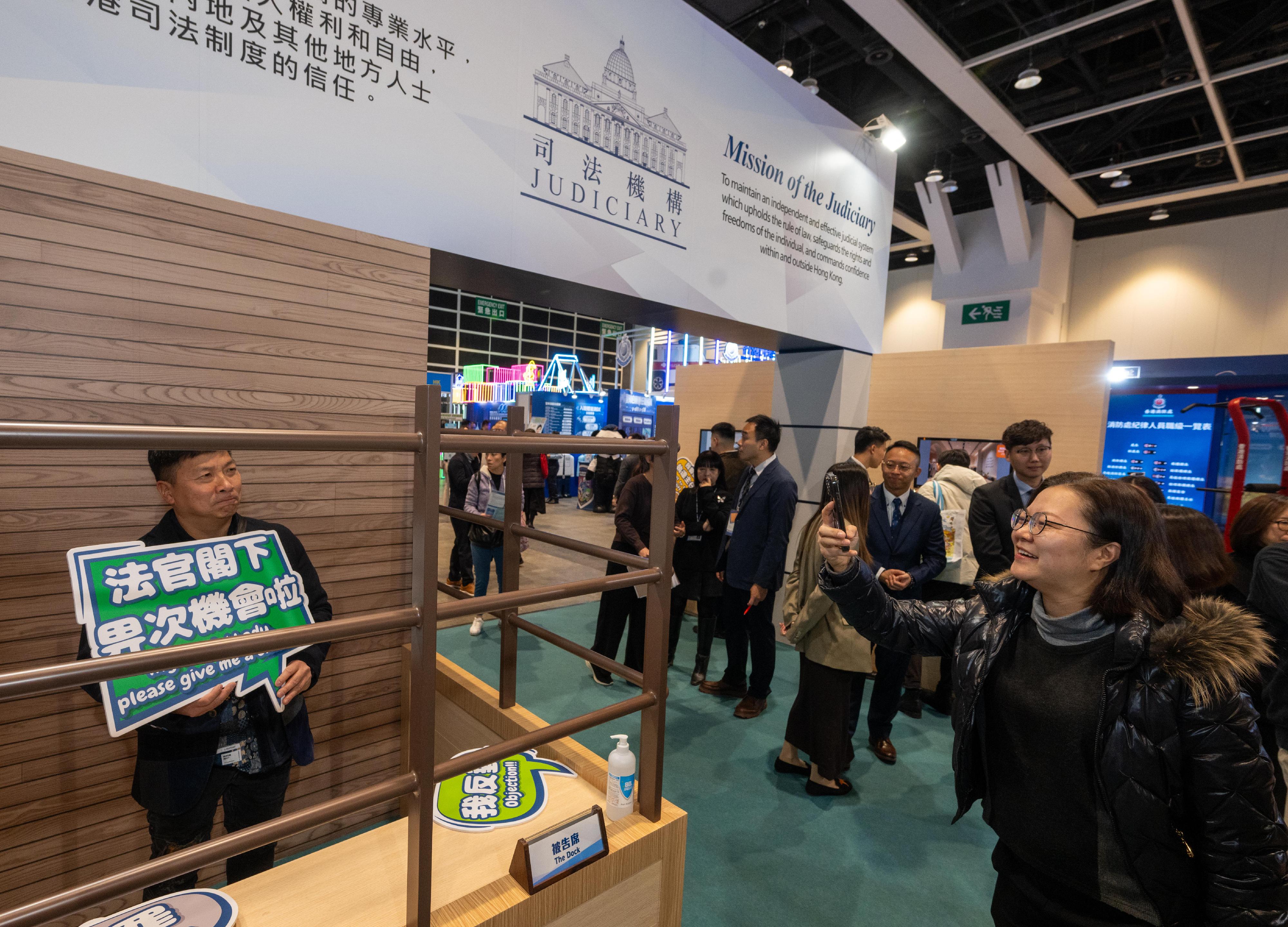 The Judiciary's dedicated booth set up at the Education & Careers Expo 2026 features a mock courtroom design to highlight the career opportunities in support services for court operations. Photo shows members of the public taking photos with props while visiting the booth.