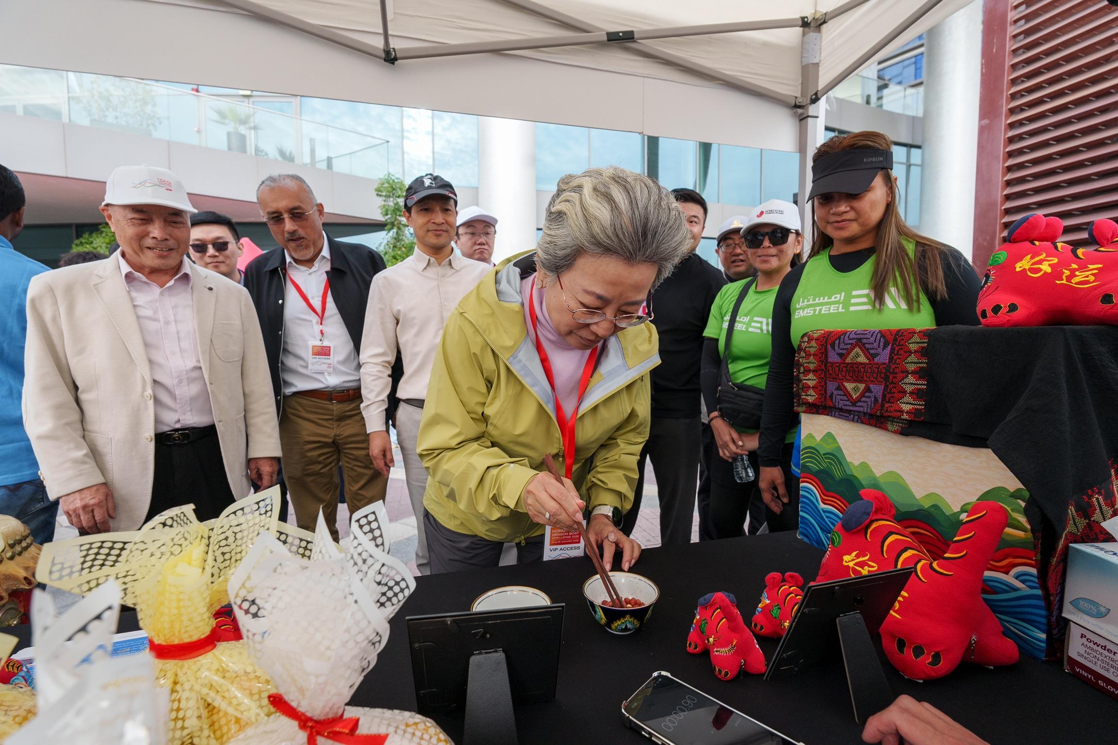 The Hong Kong Economic and Trade Office in Dubai presented the Hong Kong Dragon Boat Challenge 2026 in Dubai, the United Arab Emirates, on January 24 and 25 (Dubai time). Promotional booths were set up at the venue to promote the traditional culture and latest information of Hong Kong. Photo shows the Consul-General of the People's Republic of China in Dubai, Ms Ou Boqian (centre), taking part in an interactive cultural game at a booth.