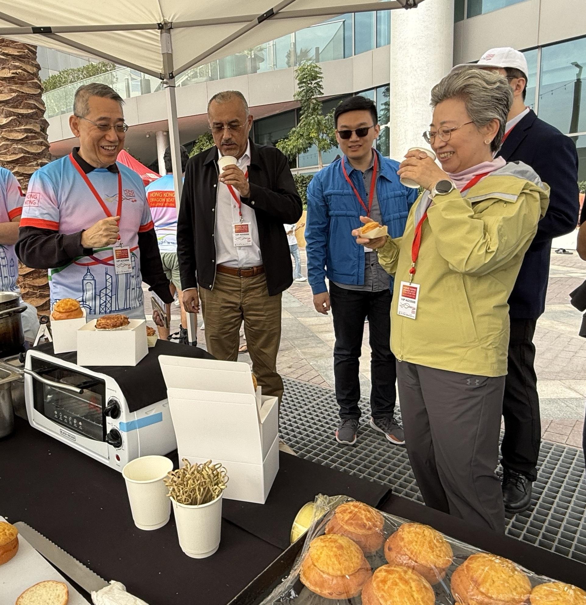 The Hong Kong Economic and Trade Office in Dubai (Dubai ETO) presented the Hong Kong Dragon Boat Challenge 2026 in Dubai, the United Arab Emirates, on January 24 and 25 (Dubai time). Promotional booths were set up at the venue to promote the traditional culture and latest information of Hong Kong. Photo shows the Consul-General of the People's Republic of China in Dubai, Ms Ou Boqian (right), trying authentic Hong Kong flavours at a booth, onlooking is the Director-General of Dubai ETO, Mr Simon Chan (left).