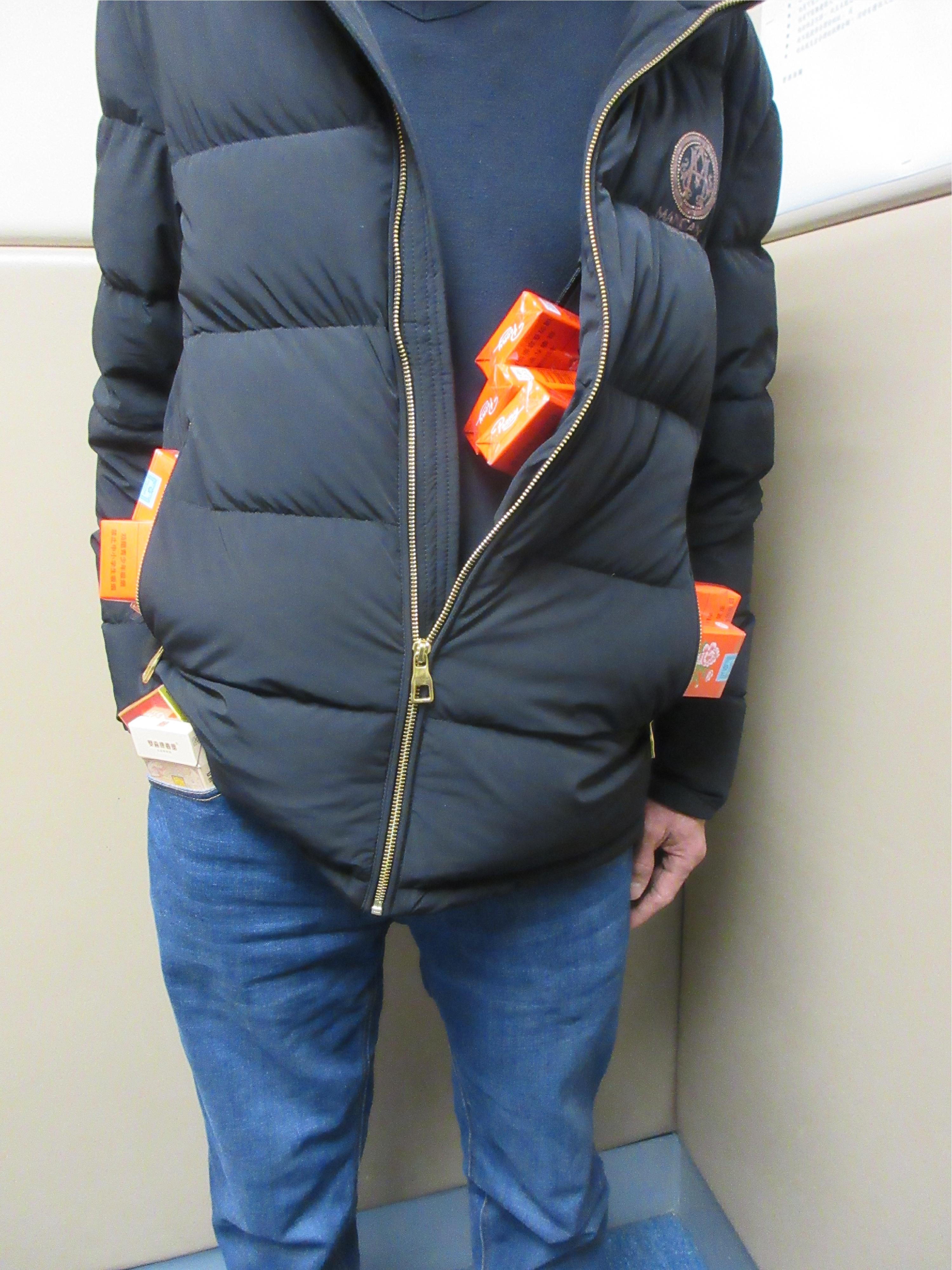 An incoming male passenger was sentenced to six weeks' imprisonment and fined $600 at the Fanling Magistrates' Courts today (February 2) for possessing duty-not-paid cigarettes and failing to declare them to Customs officers, in contravention of the Dutiable Commodities Ordinance.  Photo shows the passenger concealing the duty-not-paid cigarettes inside the pockets of his jacket and trousers.