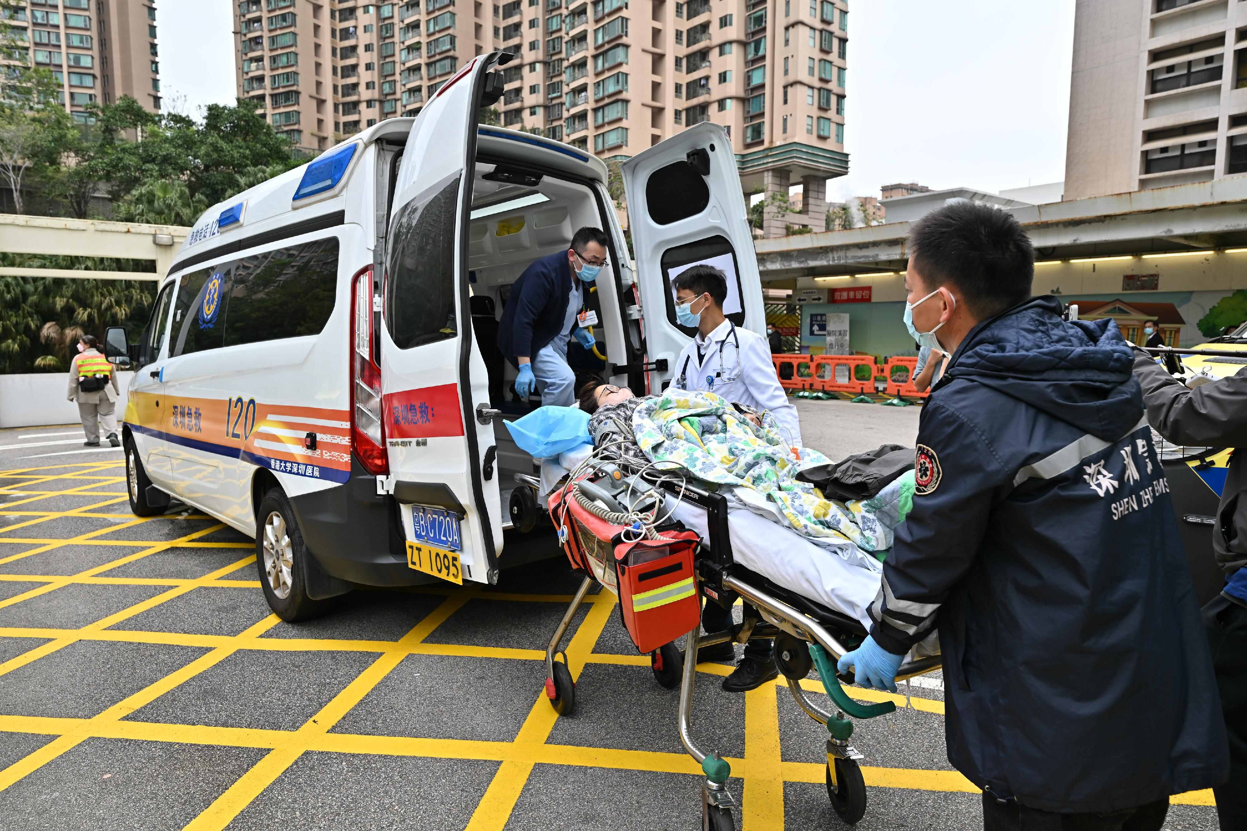 香港特別行政區政府今日（二月十日）聯同廣東省和深圳市政府就「大灣區跨境直通救護車試行計劃」進行首次北向轉運演練。圖示參與演練的人員模擬運送病人離開伊利沙伯醫院，前往香港大學深圳醫院。