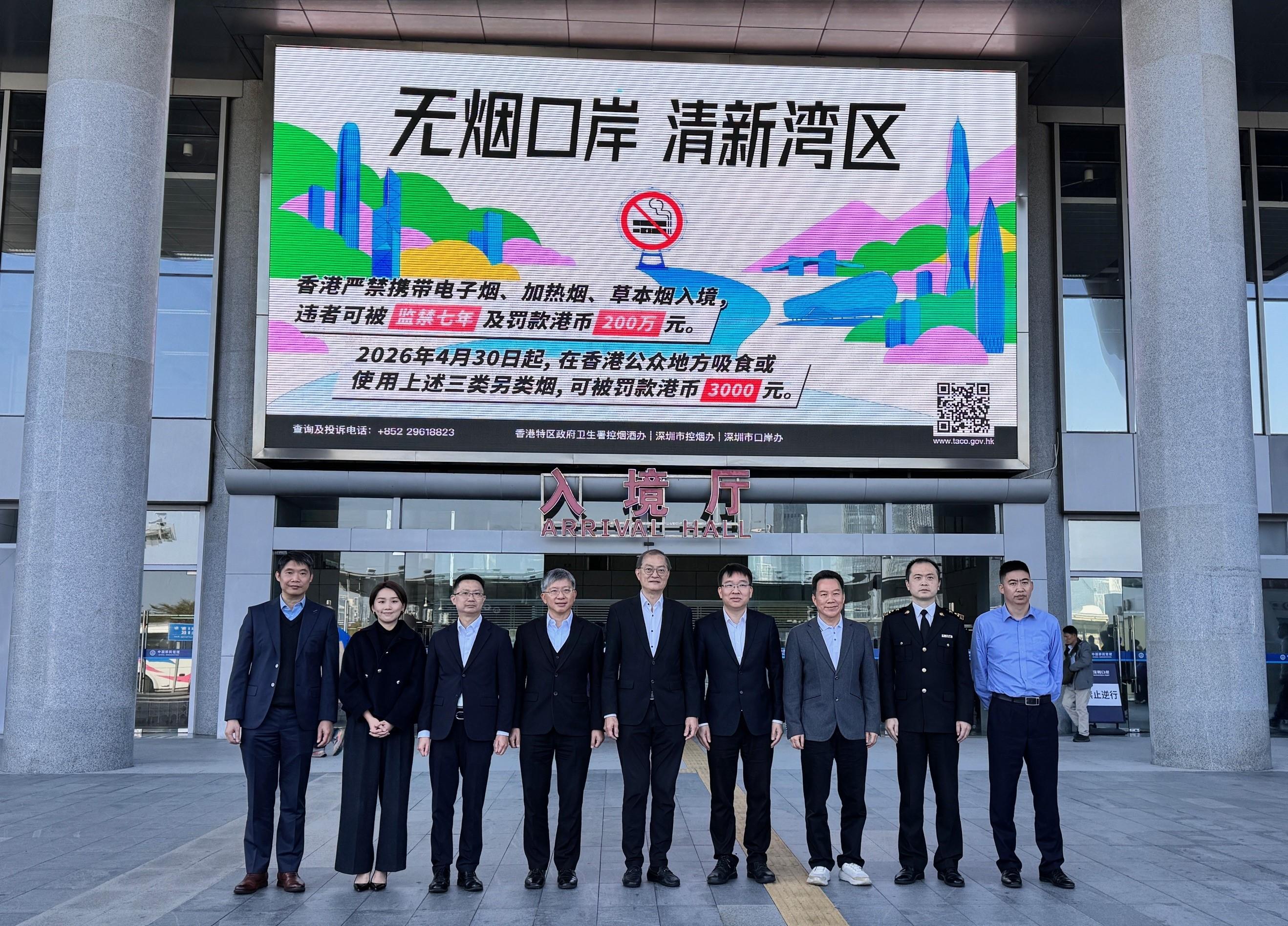 醫務衞生局（醫衞局）局長盧寵茂教授與深圳市衞生健康委員會副主任李創今日（二月十一日）在深圳會面，持續深化深港兩地在醫療衞生方面的合作。圖示盧寵茂教授（中）、李創（右四）、醫衞局常任秘書長陳松青（左四）、醫衞局高級顧問（局長辦公室）樊敬文醫生（左三）和其他兩地政府人員於深圳灣口岸一塊提醒入境香港旅客關於本港控煙措施的屏幕下合照。