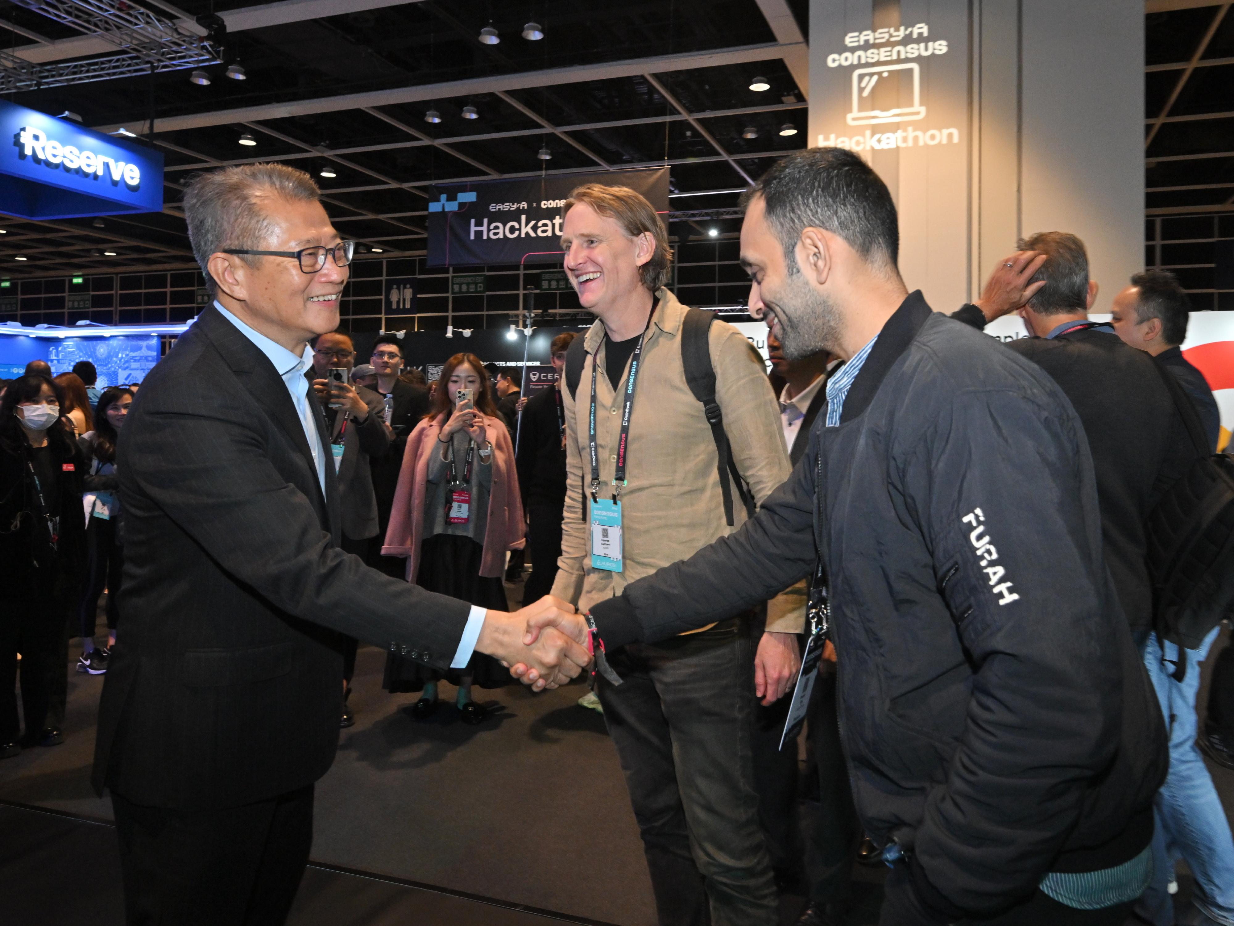 The Financial Secretary, Mr Paul Chan, attended the Consensus Hong Kong 2026 today (February 11). Photo shows Mr Chan (left) visiting an exhibition booth.