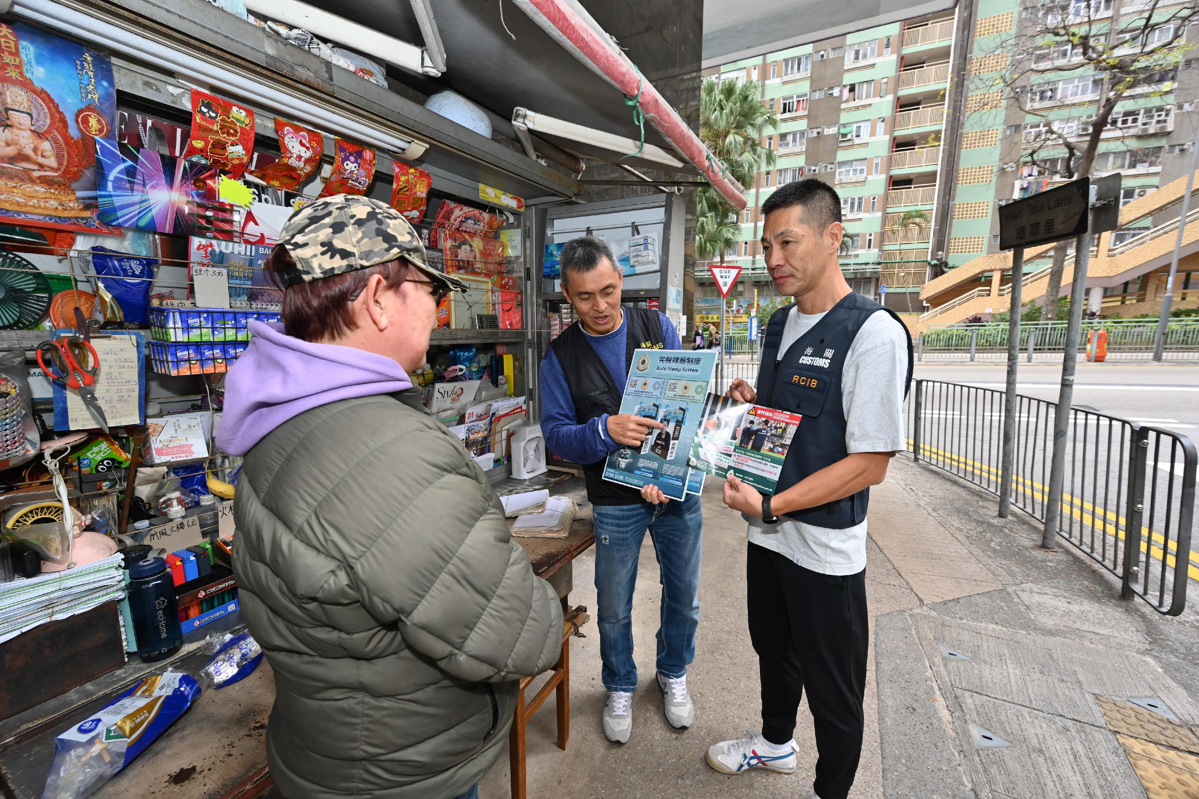 Hong Kong Customs on February 10 and today (February 12) publicised the Duty Stamp System to cigarette retailers near the Hing Wah (2) Estate, Yue Wan Estate, Siu Sai Wan Estate and Wan Tsui Estate in Eastern District. Photo shows Customs officers introducing anti-illicit cigarette messages and the Duty Stamp System to a merchant.