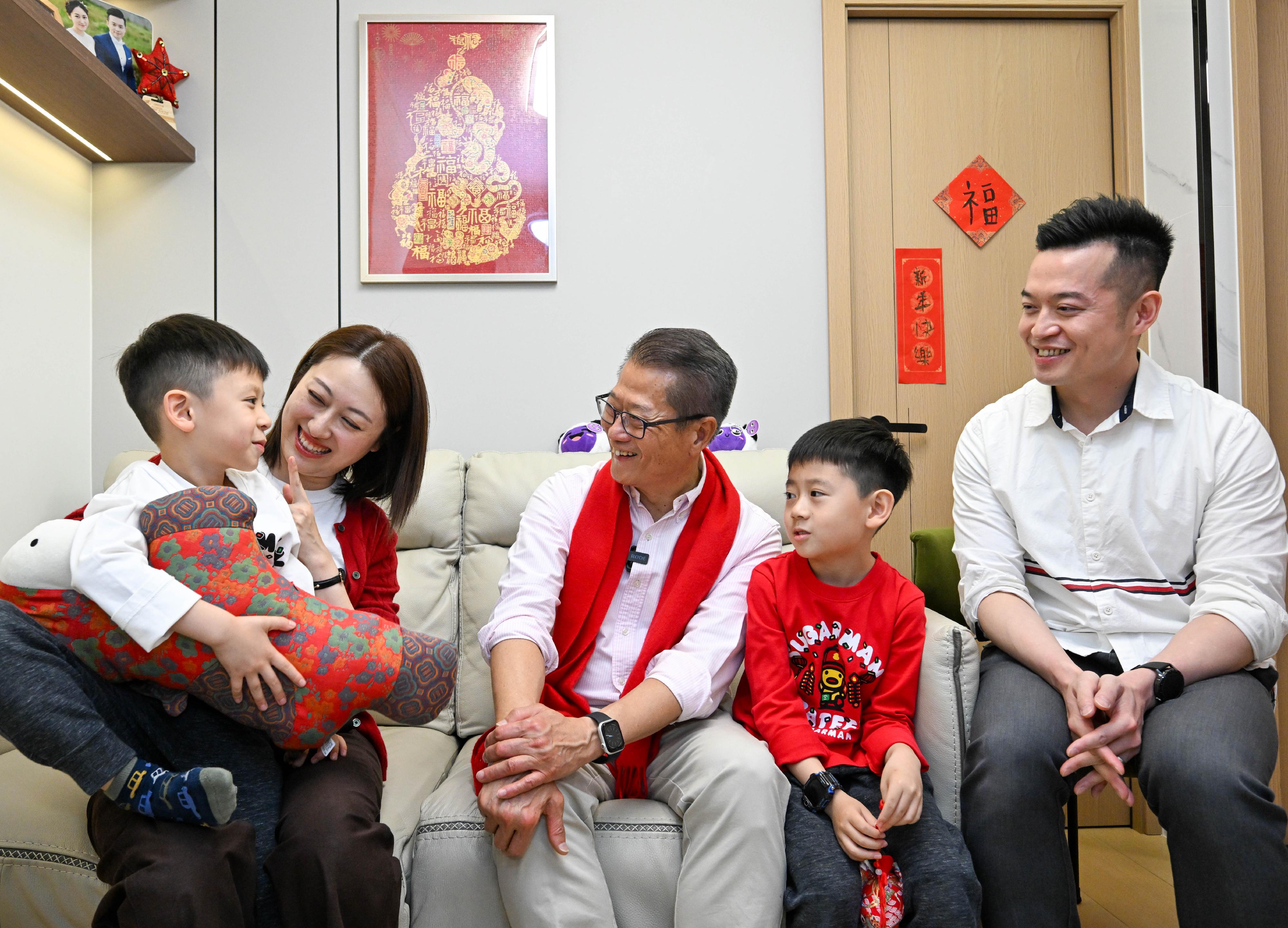 The Financial Secretary, Mr Paul Chan (centre), visits a family living in Sai Wan in warm conversations and send them greetings.