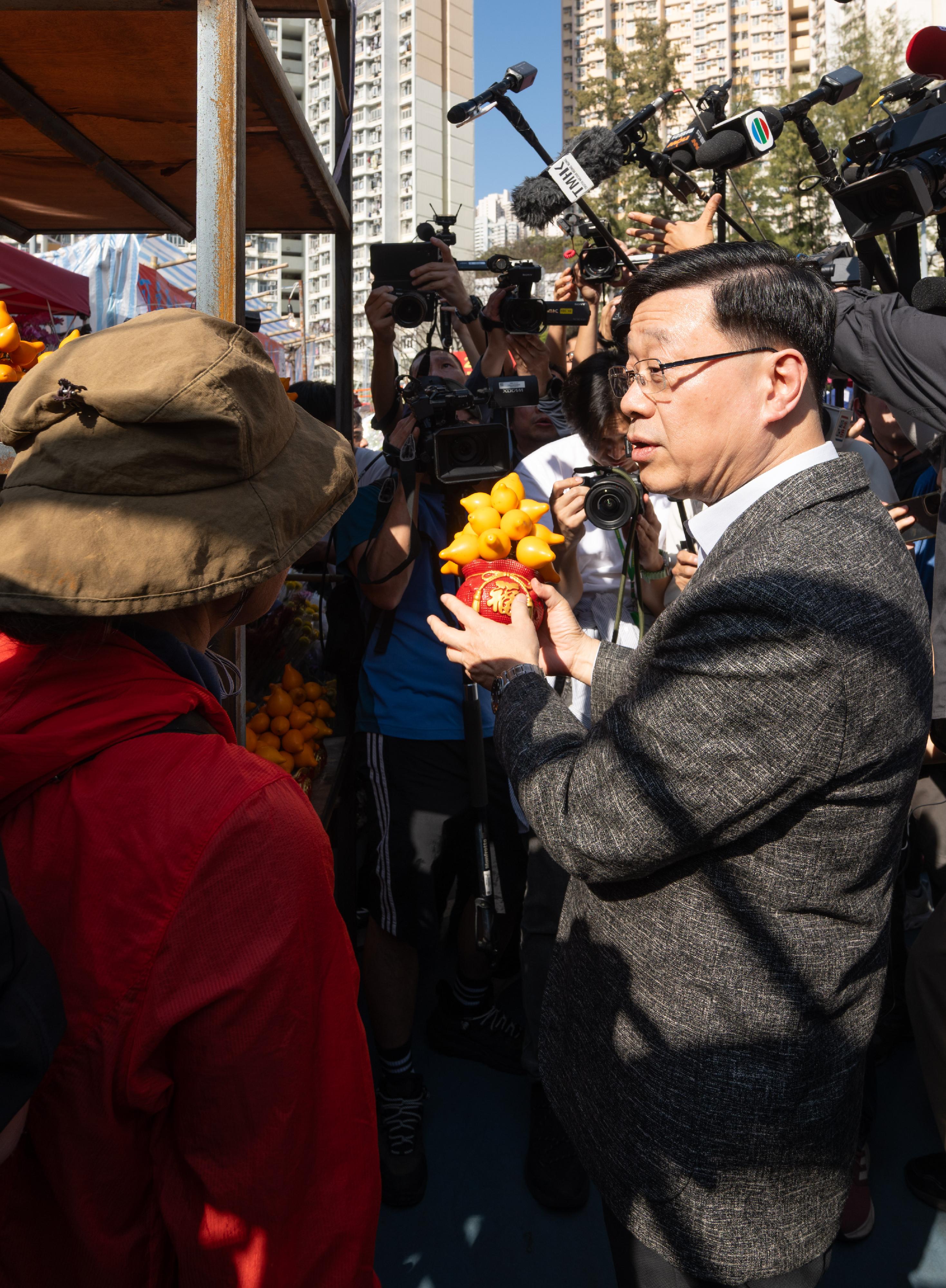 行政長官李家超今日（二月十六日）到訪觀塘遊樂場農曆新年年宵市場。圖示李家超（右）購買年花。