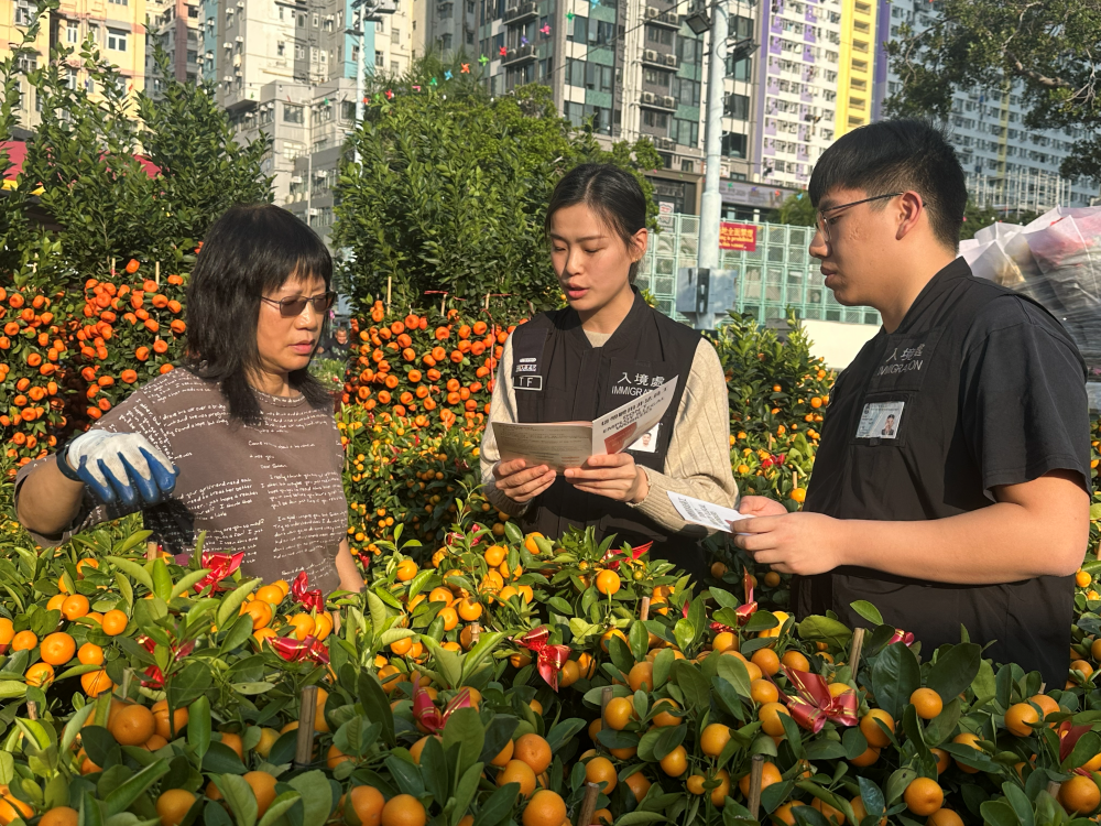 入境事務處於二月六日至昨日（二月十五日）在全港多區展開反非法勞工行動。圖示入境事務處人員向年宵市場檔主派發「切勿聘用非法勞工」的宣傳單張。