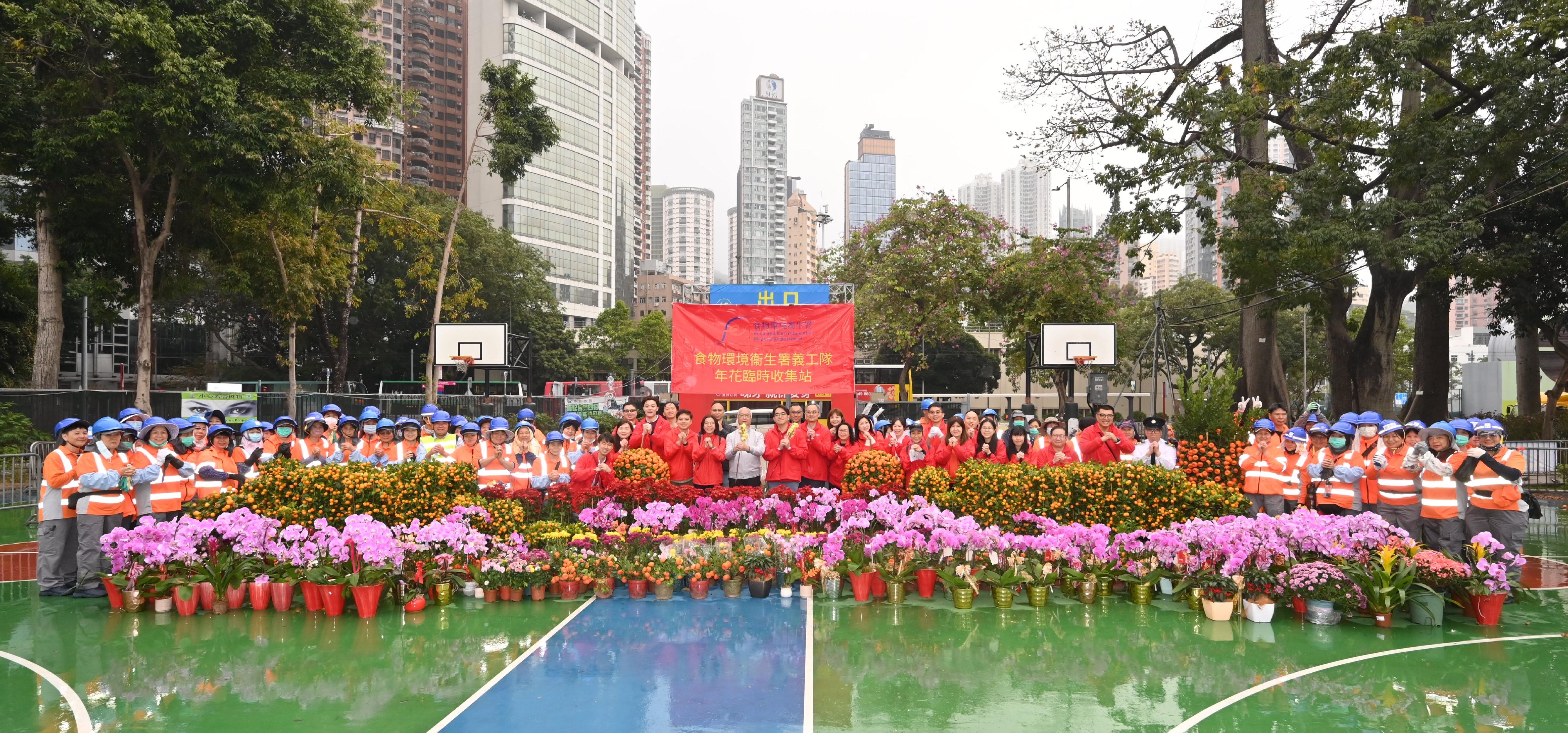 The 2026 Lunar New Year (LNY) fairs concluded successfully at 7am today (February 17). Volunteer teams made up of the Food and Environmental Hygiene Department staff assisted the department to deliver unsold pots of flowers and plants donated by LNY fair licensees to elderly home/residential care homes for person with disabilities and public hospitals. Photo shows the Secretary for Environment and Ecology, Mr Tse Chin-wan, and the Director of Food and Environmental Hygiene, Mr Donald Ng, taking a group photo with the volunteer teams and cleansing workers at the temporary flower collection point.