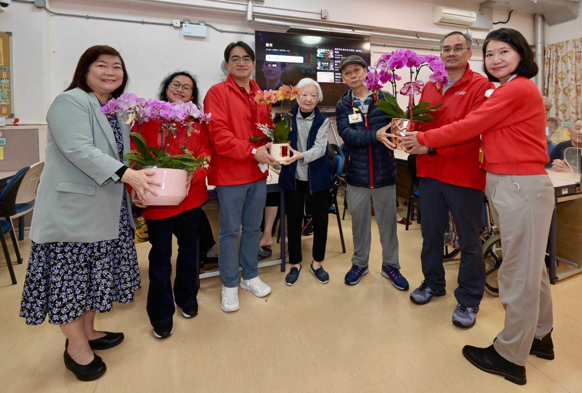 The 2026 Lunar New Year (LNY) fairs concluded successfully at 7am today (February 17). Volunteer teams made up of the Food and Environmental Hygiene Department staff assisted the department to deliver unsold pots of flowers and plants donated by LNY fair licensees to elderly home/residential care homes for person with disabilities and public hospitals. Photo shows the Director of Food and Environmental Hygiene, Mr Donald Ng (third left), giving flowers to elderly persons at a residential care home for the elderly.