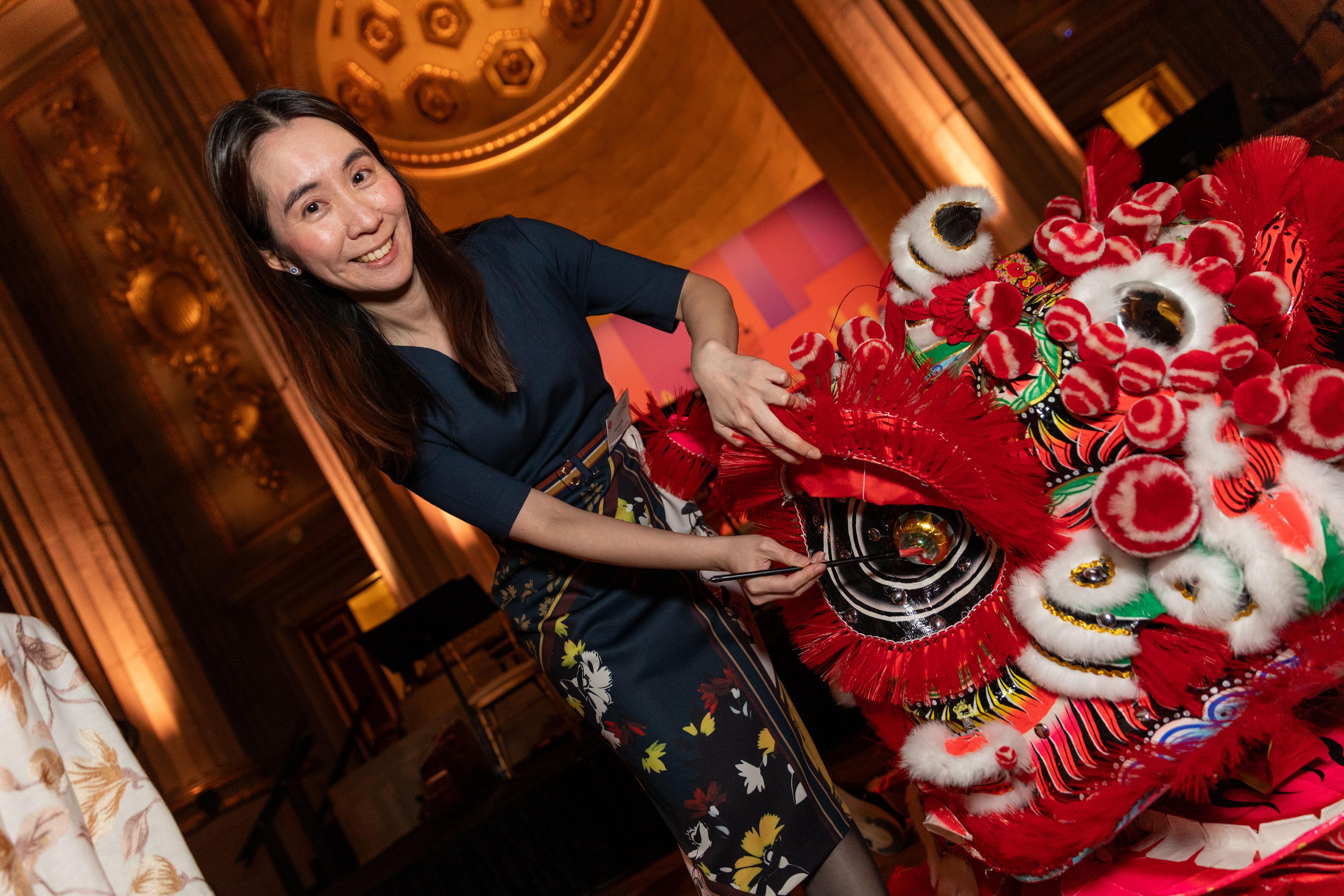 The Hong Kong Economic and Trade Office in Washington DC (HKETO, Washington DC) hosted a Chinese New Year reception on February 25 (Washington DC time) in Washington DC, the United States. Photo shows the Director of the HKETO, Washington DC, Ms Elania Luk, dotting the eyes of the lions to mark the start of a lion dance.