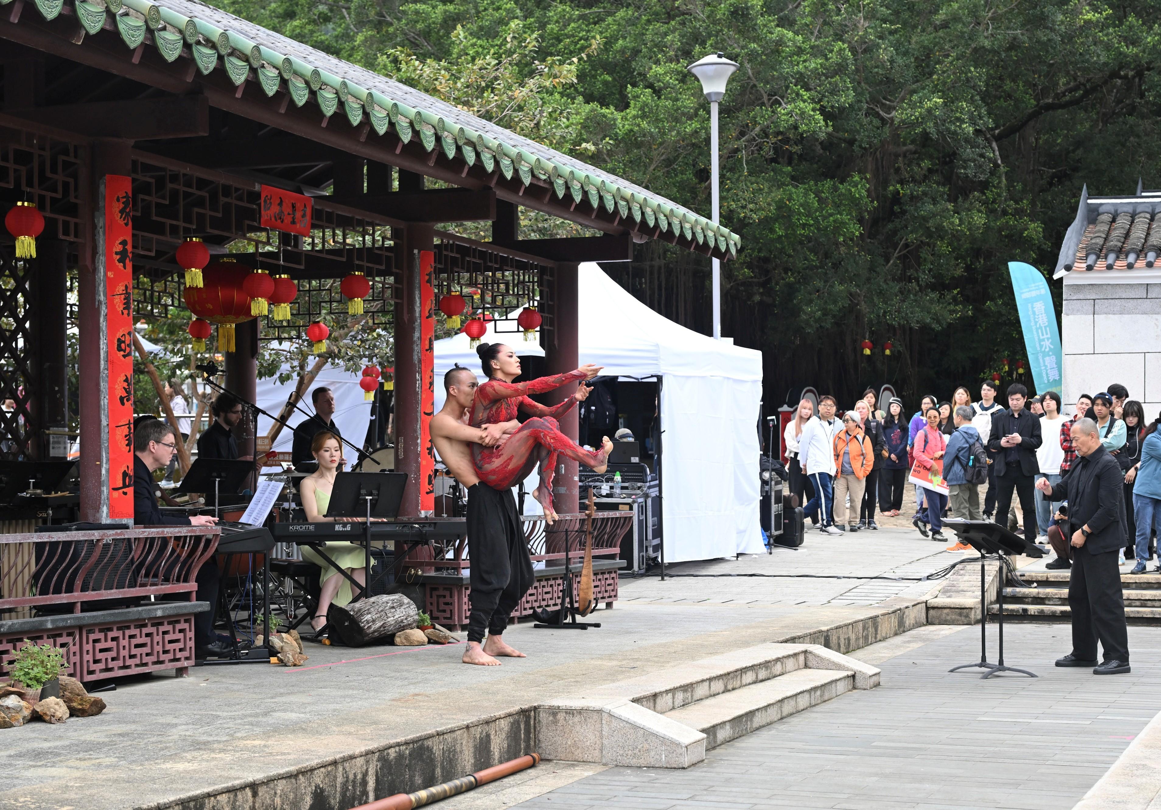 環境及生態局轄下鄉郊保育辦公室今日（三月一日）在毗鄰大鵬灣印洲塘的沙頭角荔枝窩舉行「鄉郊豐年節2026：『香港山水．聲舞』一日音樂節」。圖示音樂節藝術總監、國際享負盛名的指揮家作曲家譚盾（右一）與頂尖音樂家和舞蹈家為觀眾演出「譚盾與楊麗萍實景樂舞《春之祭‧輪迴》」。
