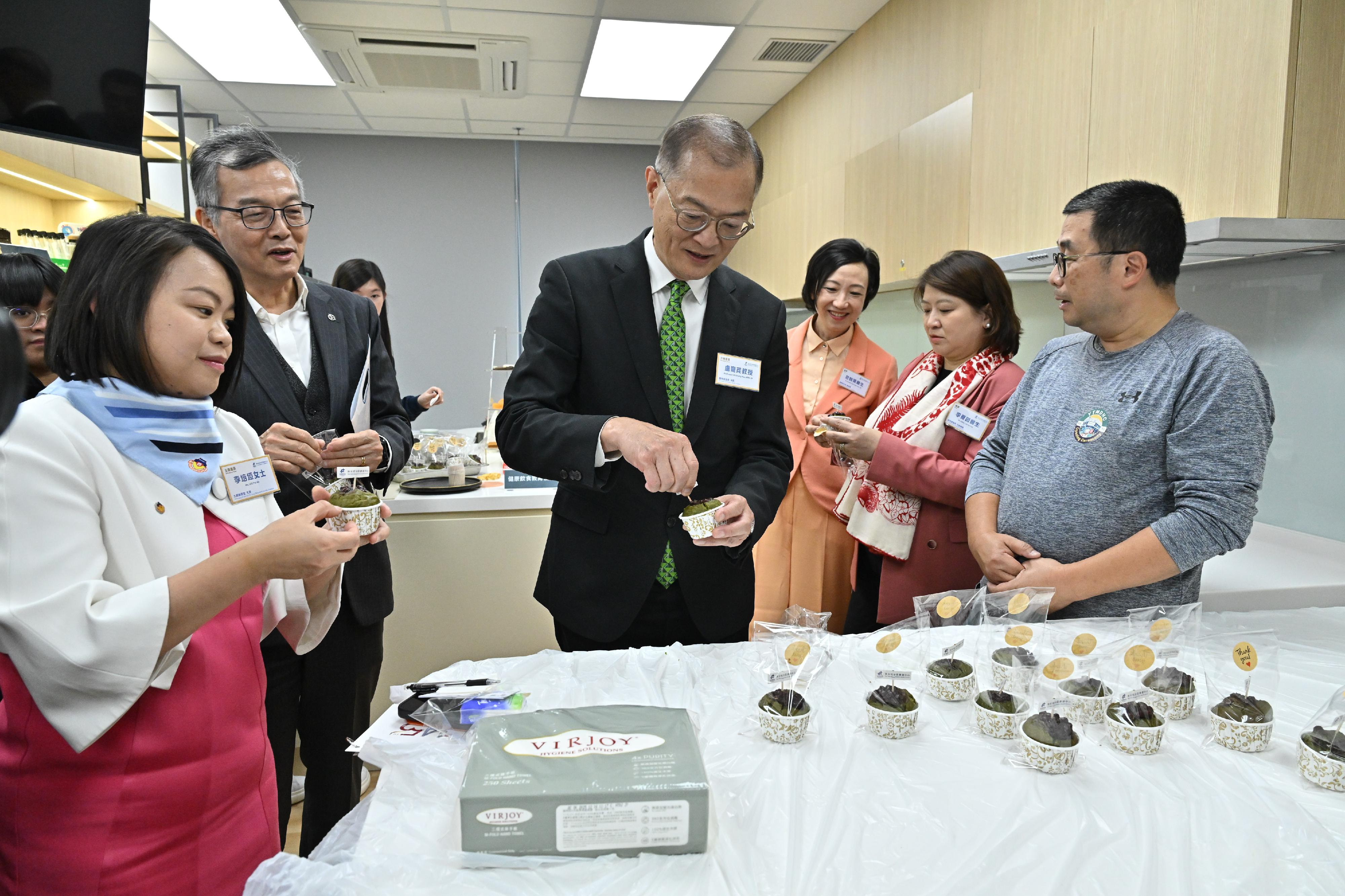 醫務衞生局（醫衞局）局長盧寵茂教授今日（三月十三日）主持油尖旺地區康健中心開幕禮暨基層醫療共同治理網絡啟動典禮。圖示盧寵茂教授（右四）在油尖旺地區康健中心的健康飲食教育室試食低糖食品。醫衞局副局長范婉雯醫生（右三）和醫院管理局行政總裁李夏茵醫生（右二）亦有陪同。