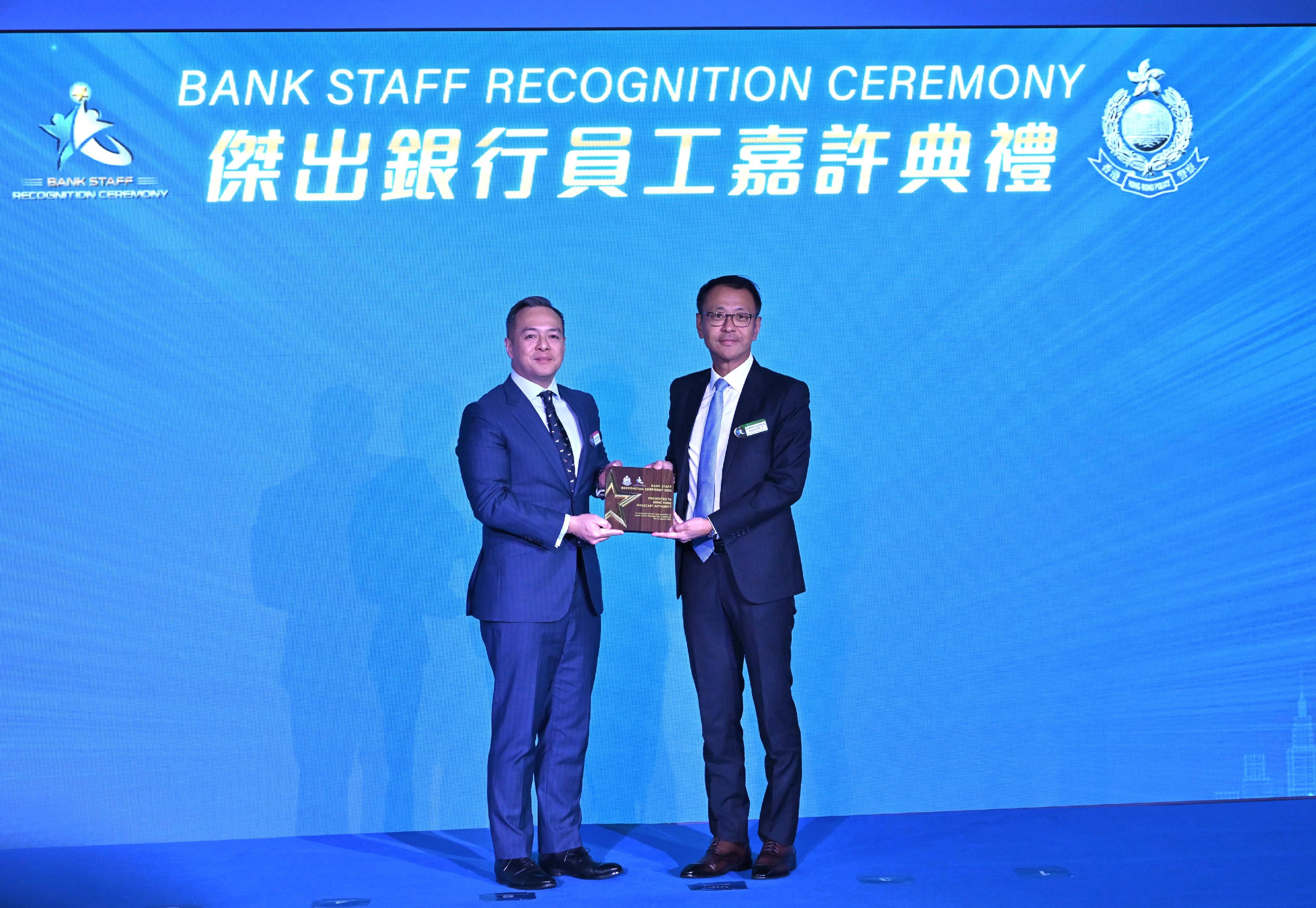 香港警務處今日（三月二十日）舉辦「2026傑出銀行員工嘉許典禮」。圖示警務處處長周一鳴（左）頒發紀念品給香港金融管理局助理總裁陳景宏（右）。