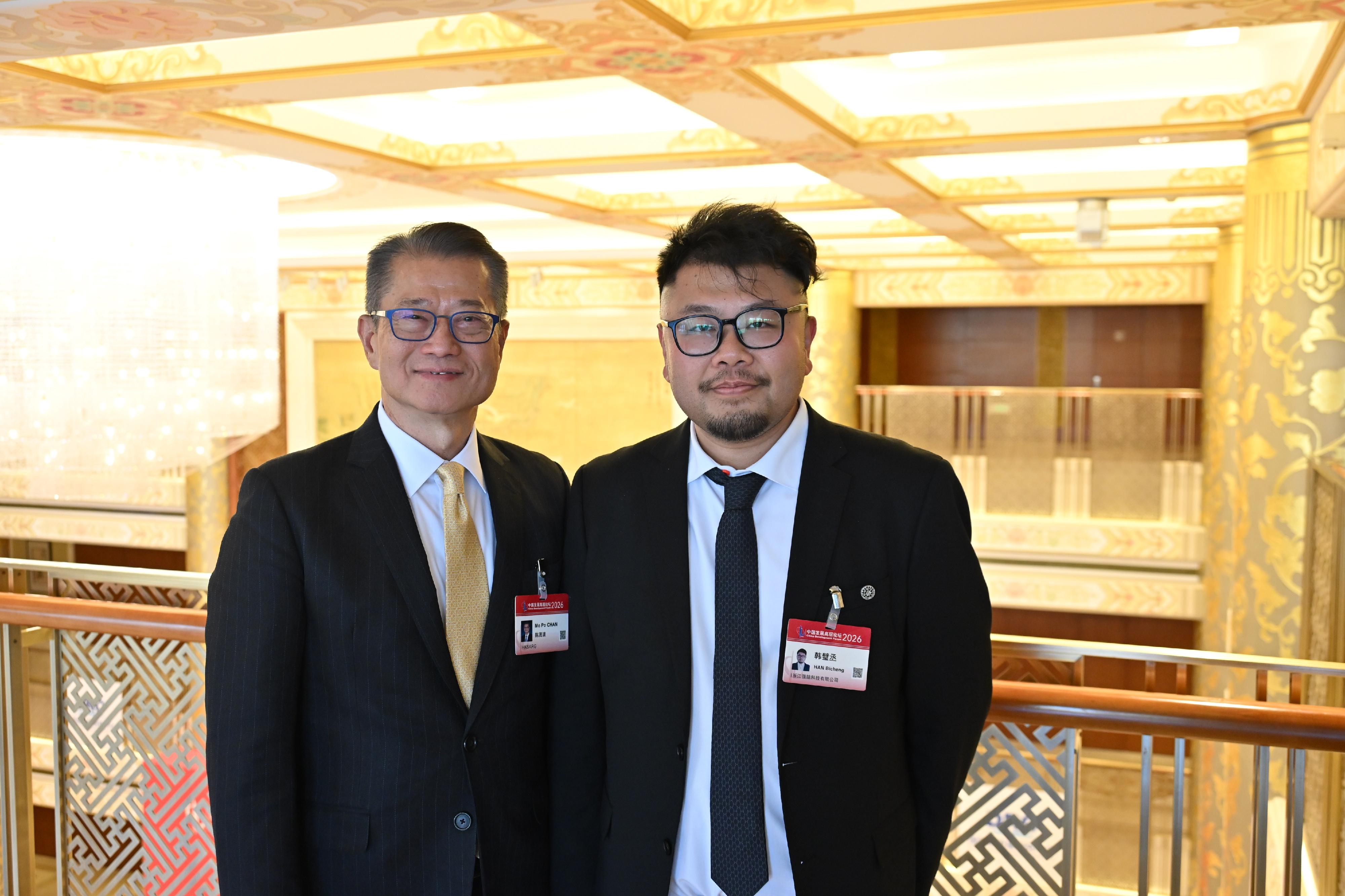 The Financial Secretary, Mr Paul Chan, continued his visit in Beijing today (March 22). Photo shows Mr Chan (left) attending the China Development Forum 2026 and taking a photo with the Founder and the Chief Executive Officer of BrainCo, Dr Han Bicheng (right).