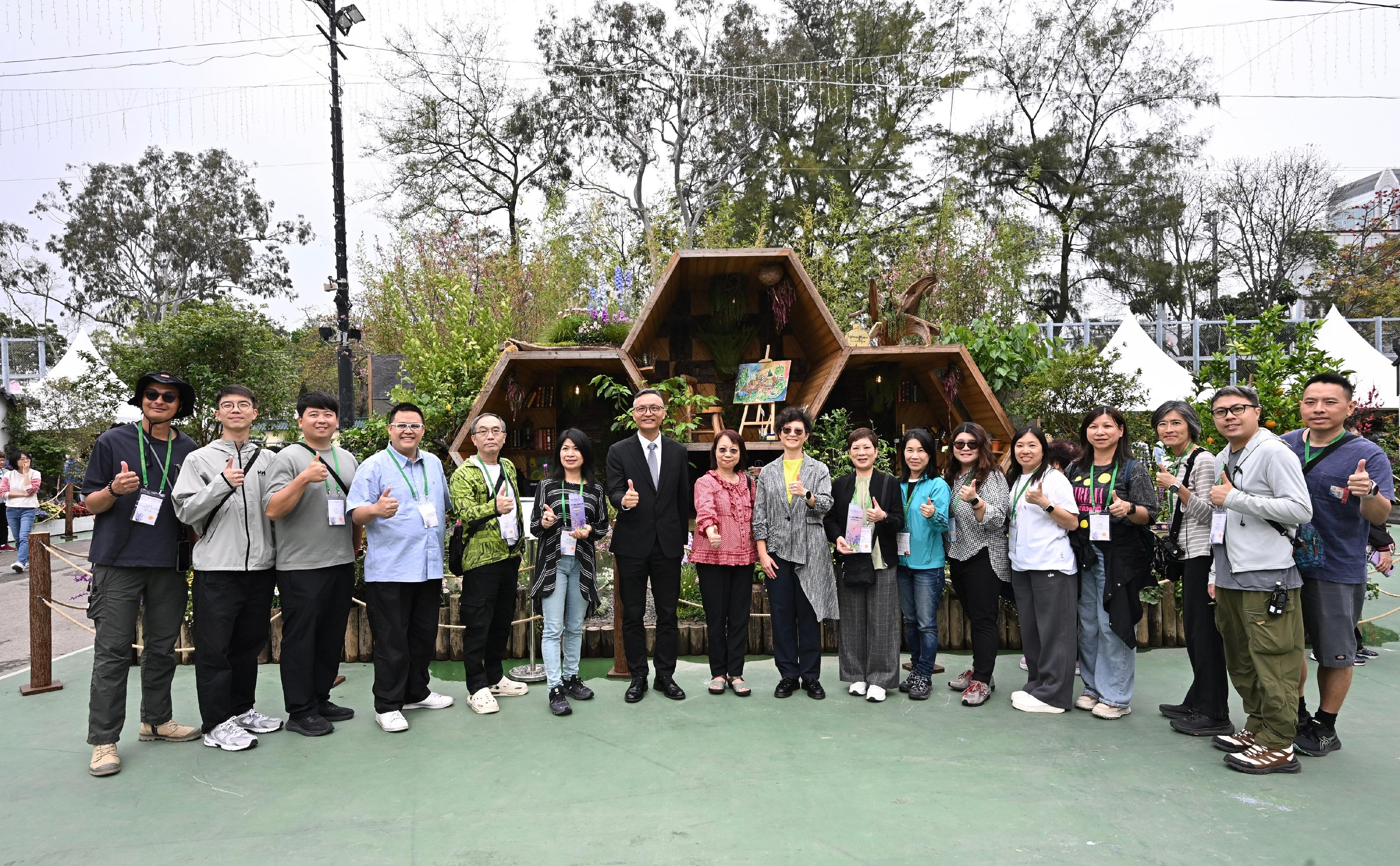 二○二六年香港花卉展覽現於維多利亞公園舉行，場內展出康樂及文化事務署（康文署）東方園圃及西方園圃比賽的得獎作品。圖示康文署副署長（康樂事務）徐曉露（左九）、康文署助理署長（康樂事務）王文煌（左七）及屯門區康樂事務辦事處員工在得獎的西方園圃「蜂巢花園」前合照。