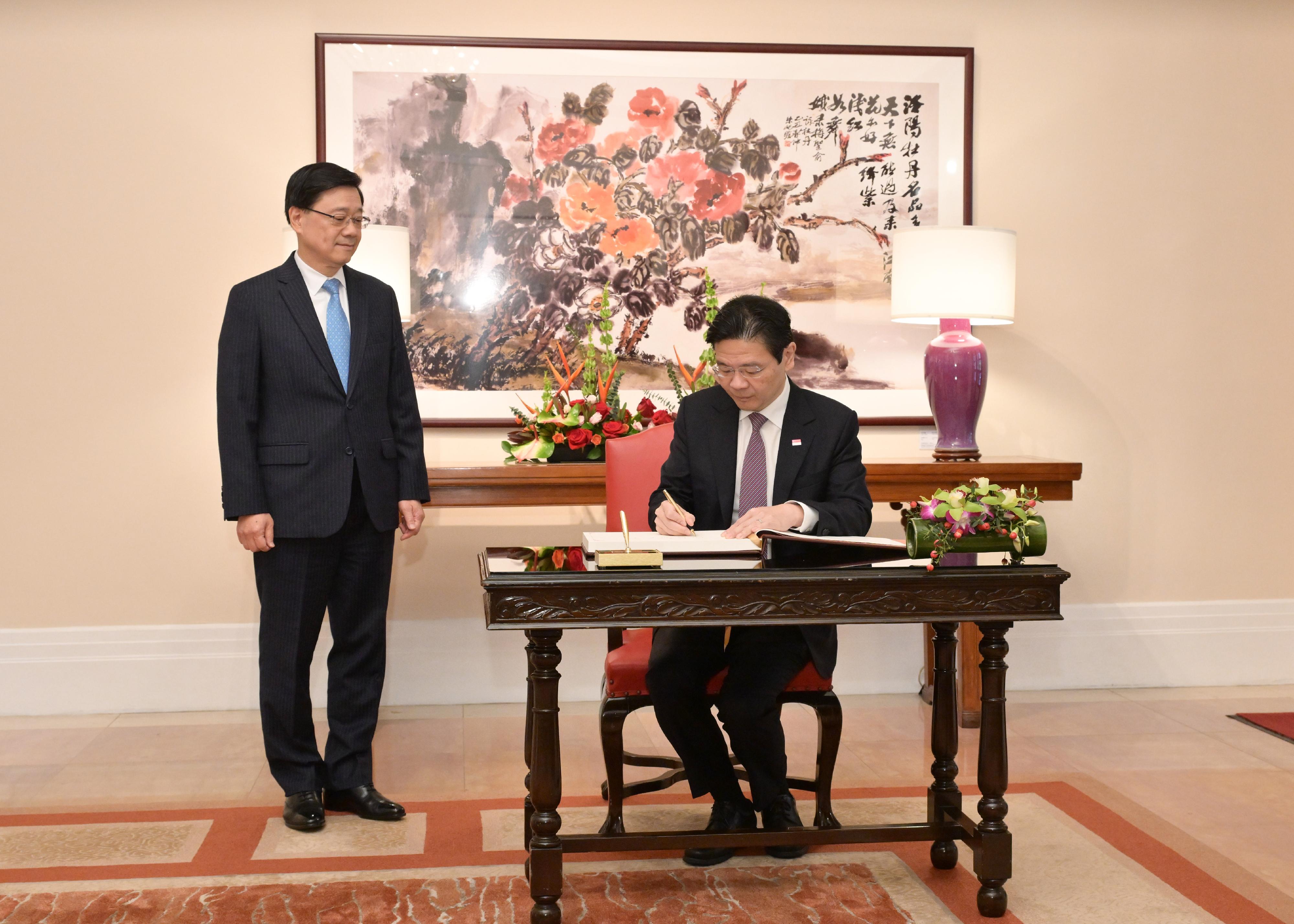 The Chief Executive, Mr John Lee (left), met with the visiting Prime Minister and Minister for Finance of Singapore, Mr Lawrence Wong (right), at Government House today (March 27). Photo shows Mr Wong signing the guest book at Government House.