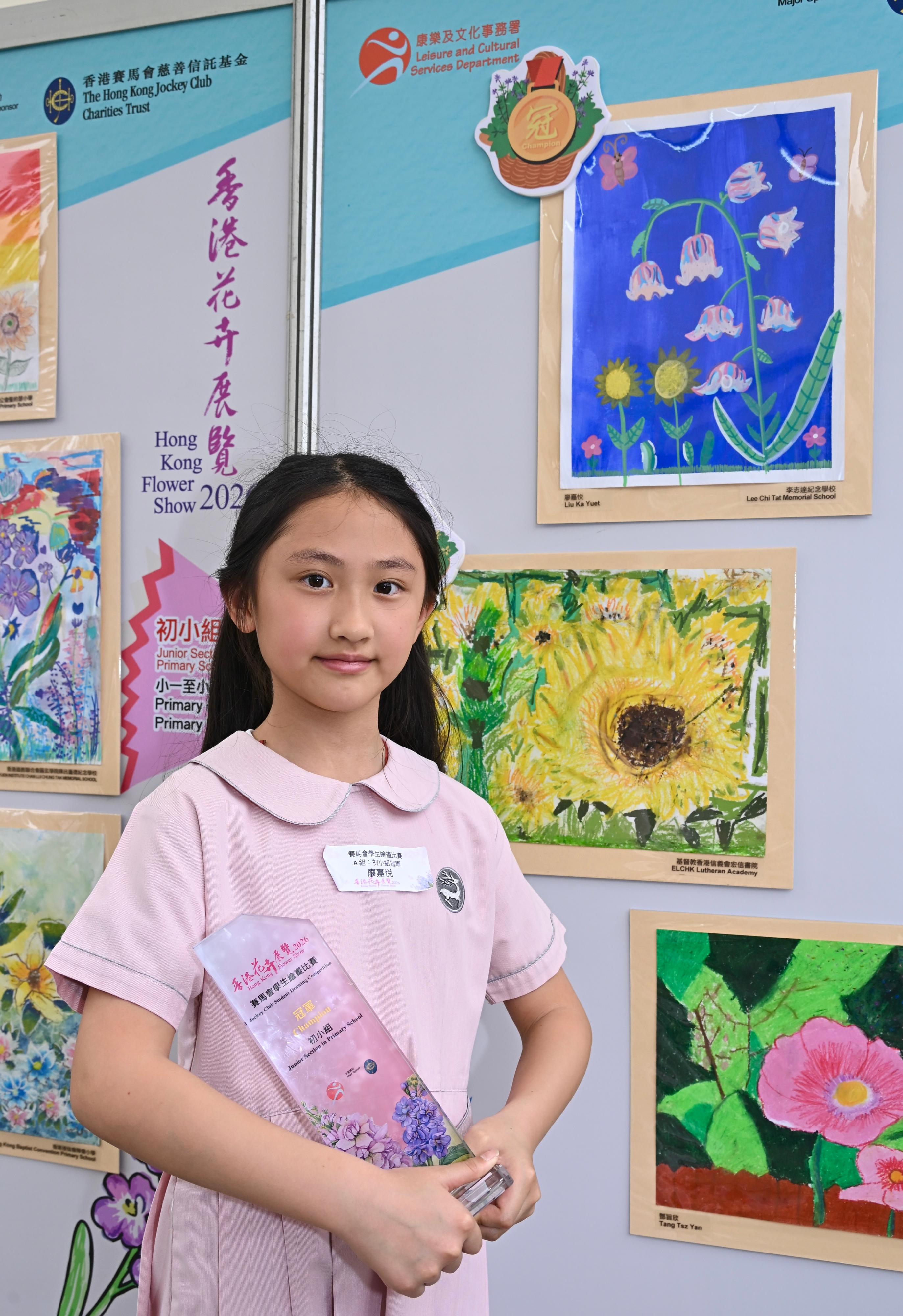 現於維多利亞公園舉行的香港花卉展覽明日（三月二十九日）晚上九時閉幕。大會在展覽期間安排了多項文娛活動，當中的賽馬會學童繪畫比賽今日（三月二十八日）舉行頒獎典禮，場內同時展出得獎作品。比賽分五個組別，圖示初小組冠軍廖嘉悦及其作品。