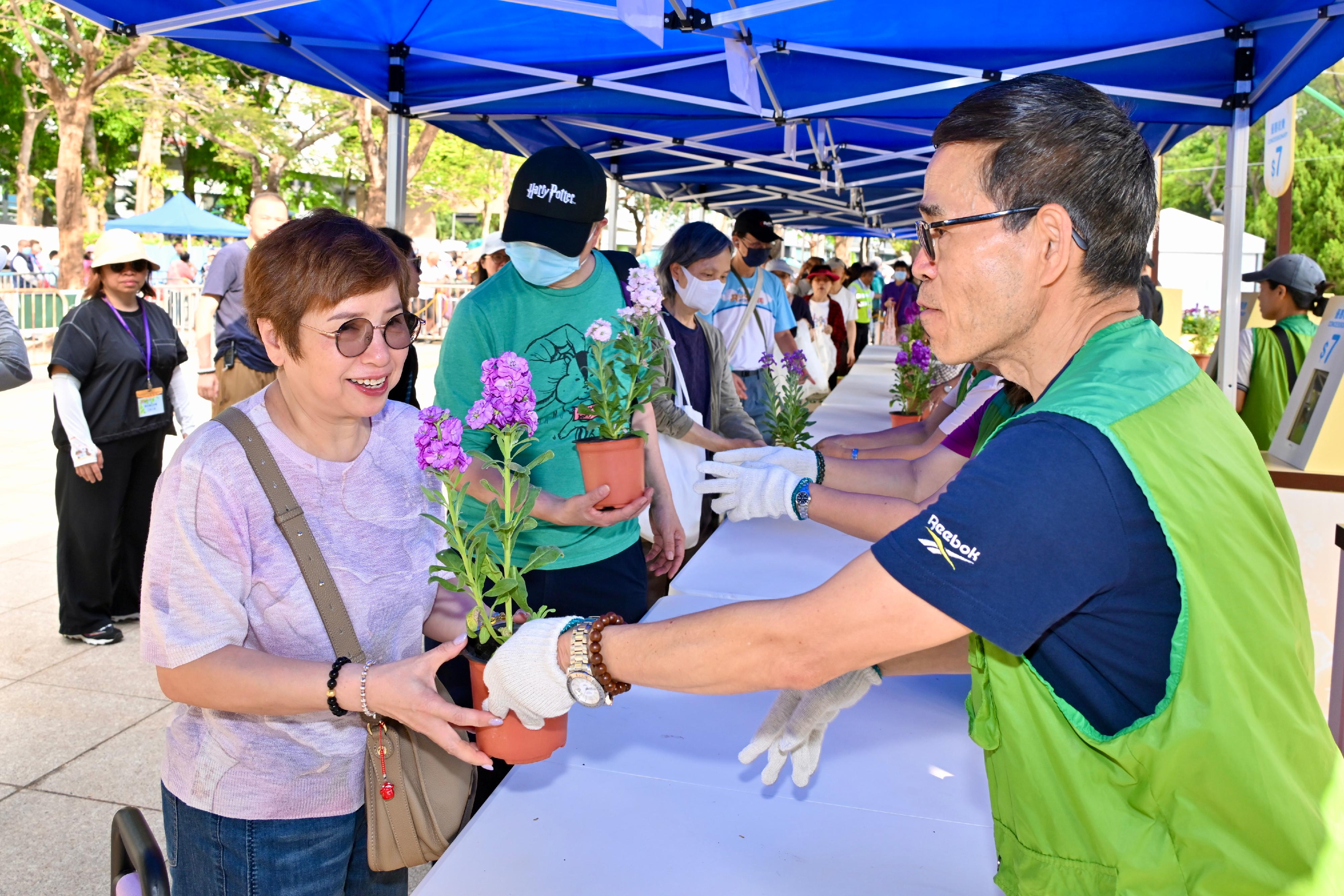 The Leisure and Cultural Services Department is once again holding a Green Recycling Day (GRD) upon the conclusion of this year's Hong Kong Flower Show. The GRD activities were held today (March 30) and will continue tomorrow (March 31) at Victoria Park to reinforce green measures and reduce waste. Photo shows a Green Volunteer distributing a potted flower to a member of the public.

