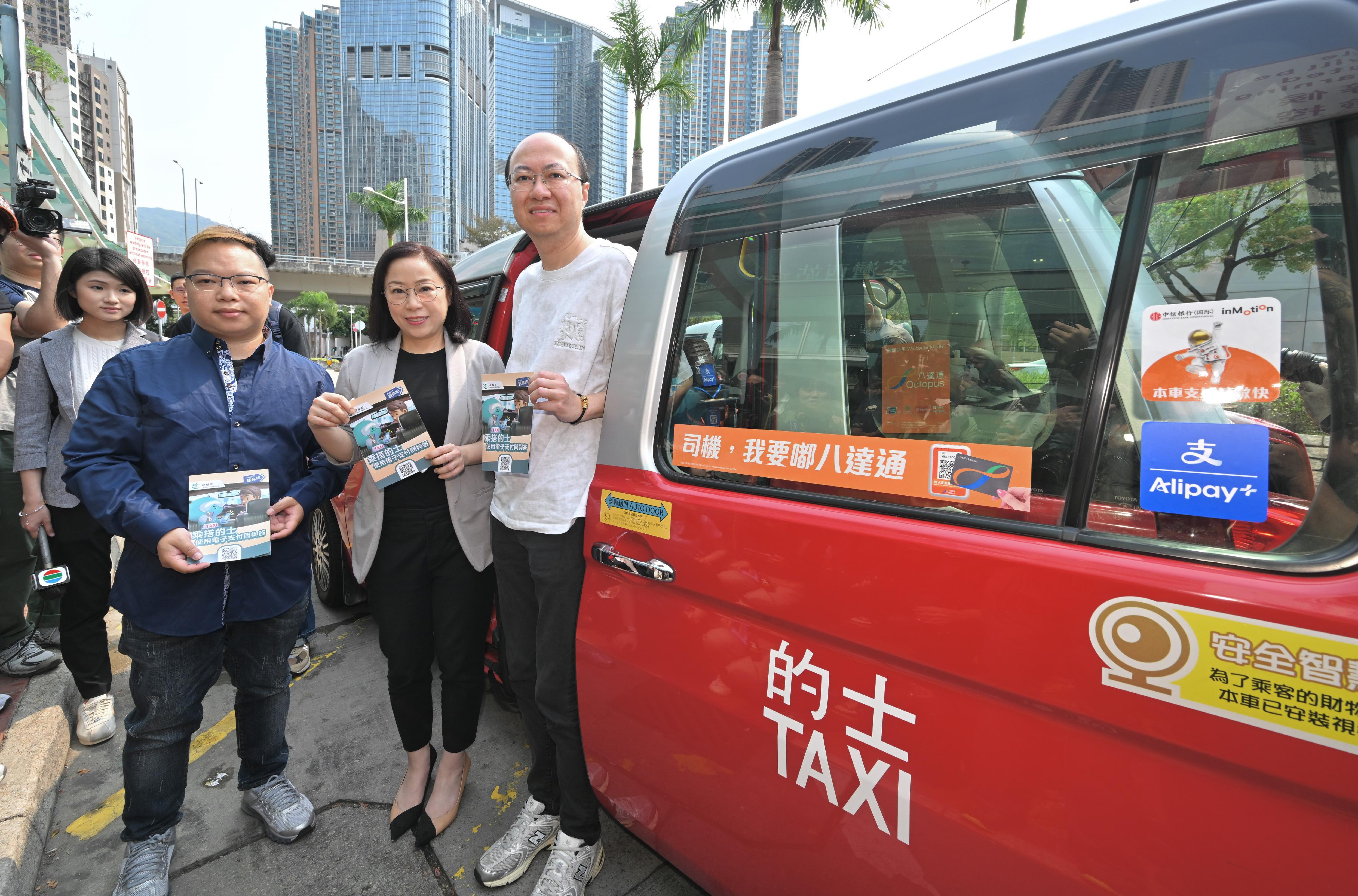 The Commissioner for Transport, Miss Winnie Tse, today (April 1) visited a taxi drop-off point in Tsuen Wan to observe the implementation of the new requirement for taxi drivers to provide electronic payment means on the first day. She was pleased to note that the overall operation was generally smooth. Photo shows Miss Tse (front row, centre), a driver and a passenger.
