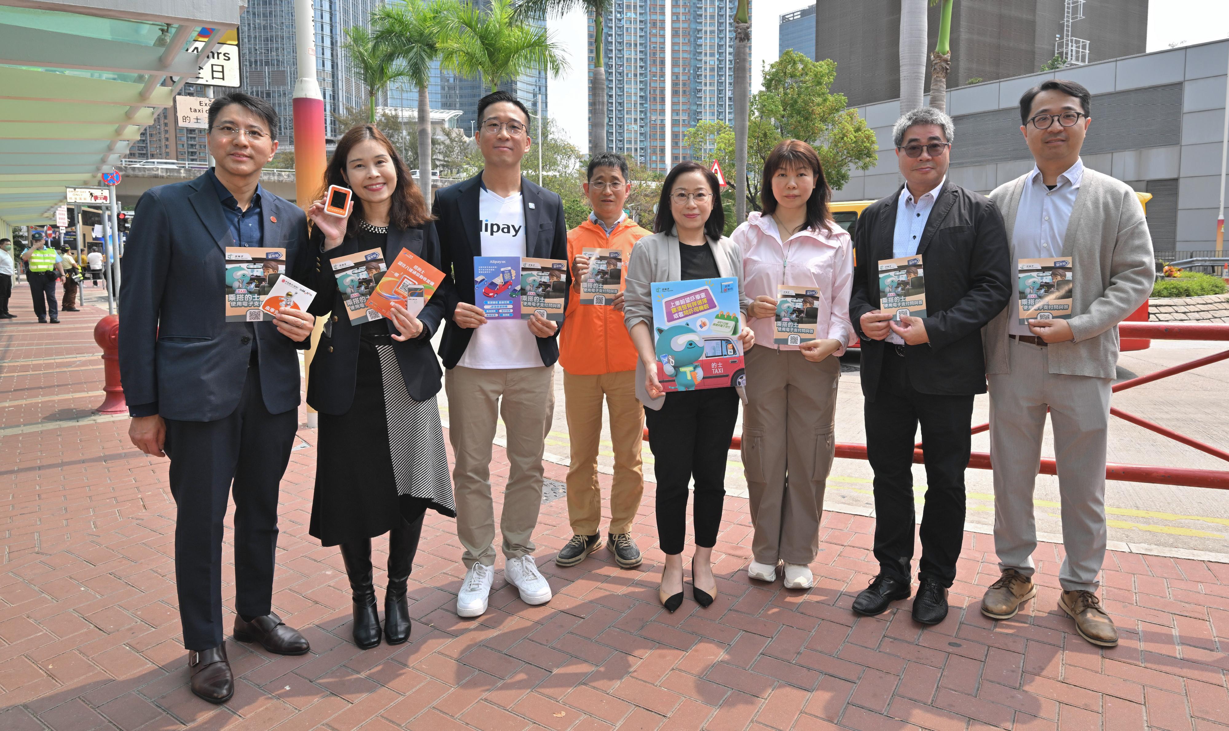 The Commissioner for Transport, Miss Winnie Tse, today (April 1) visited a taxi drop-off point in Tsuen Wan to observe the implementation of the new requirement for taxi drivers to provide electronic payment (e-payment) means on the first day. She was pleased to note that the overall operation was generally smooth. Photo shows Miss Tse (fourth right) and representatives of e-payment platforms and the taxi trade.