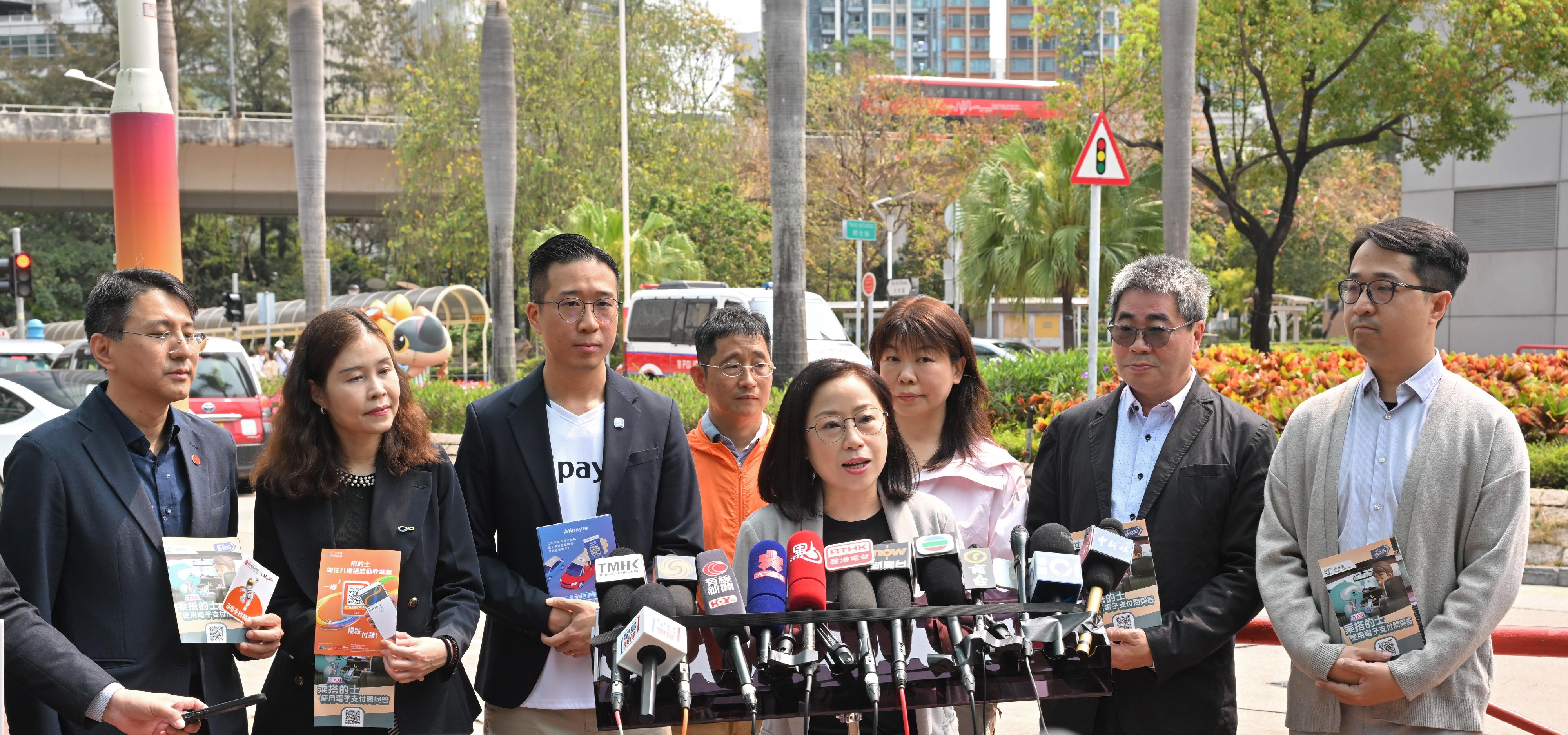 The Commissioner for Transport, Miss Winnie Tse, today (April 1) visited a taxi drop-off point in Tsuen Wan to observe the implementation of the new requirement for taxi drivers to provide electronic payment means on the first day. She was pleased to note that the overall operation was generally smooth. Photo shows Miss Tse (fourth right) meeting the media.