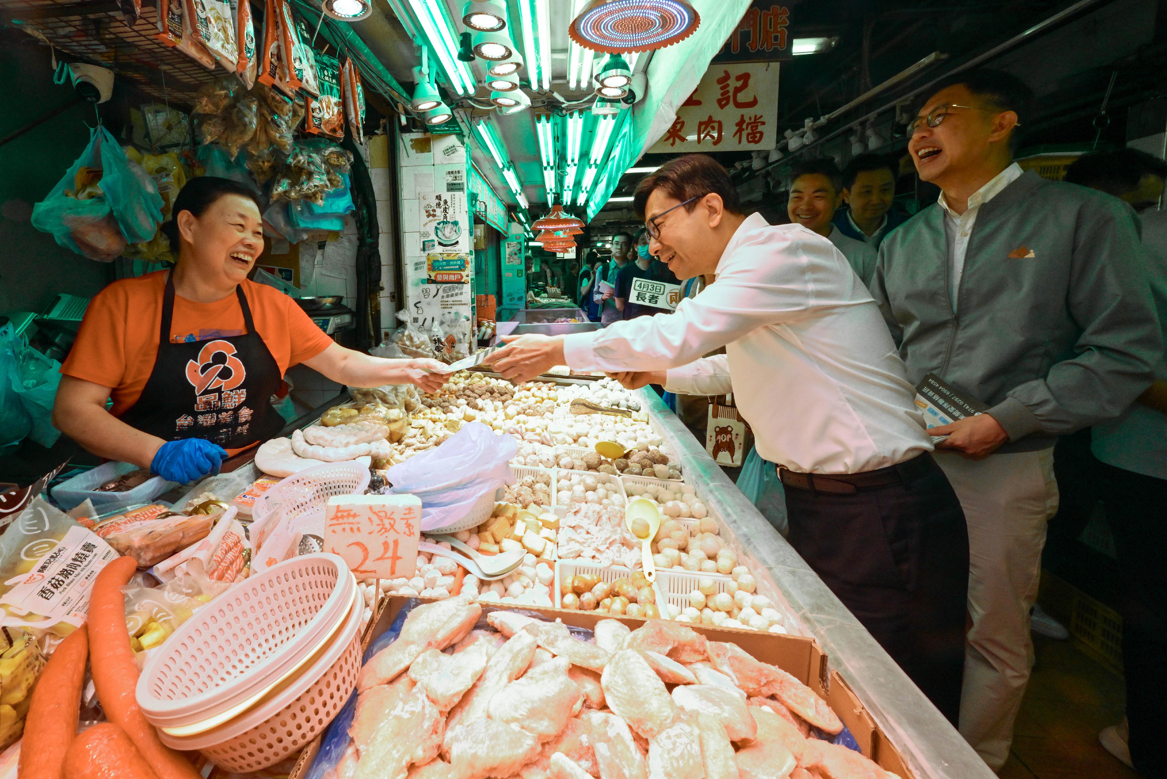 The concessionary fare under the Government Public Transport Fare Concession Scheme for the Elderly and Eligible Persons with Disabilities changes from a $2 flat fare to a "$2 flat rate or 80 per cent discount" from today (April 3). The Secretary for Labour and Welfare, Mr Chris Sun, visited Wong Tai Sin and Tiu Keng Leng to observe the implementation of "$2 flat rate or 80 per cent discount" on the first day. Photo shows Mr Sun (centre) delivering a promotion leaflet of "$2 flat rate or 80 per cent discount" to a market stall operator at Tai Shing Street Market in Wong Tai Sin.