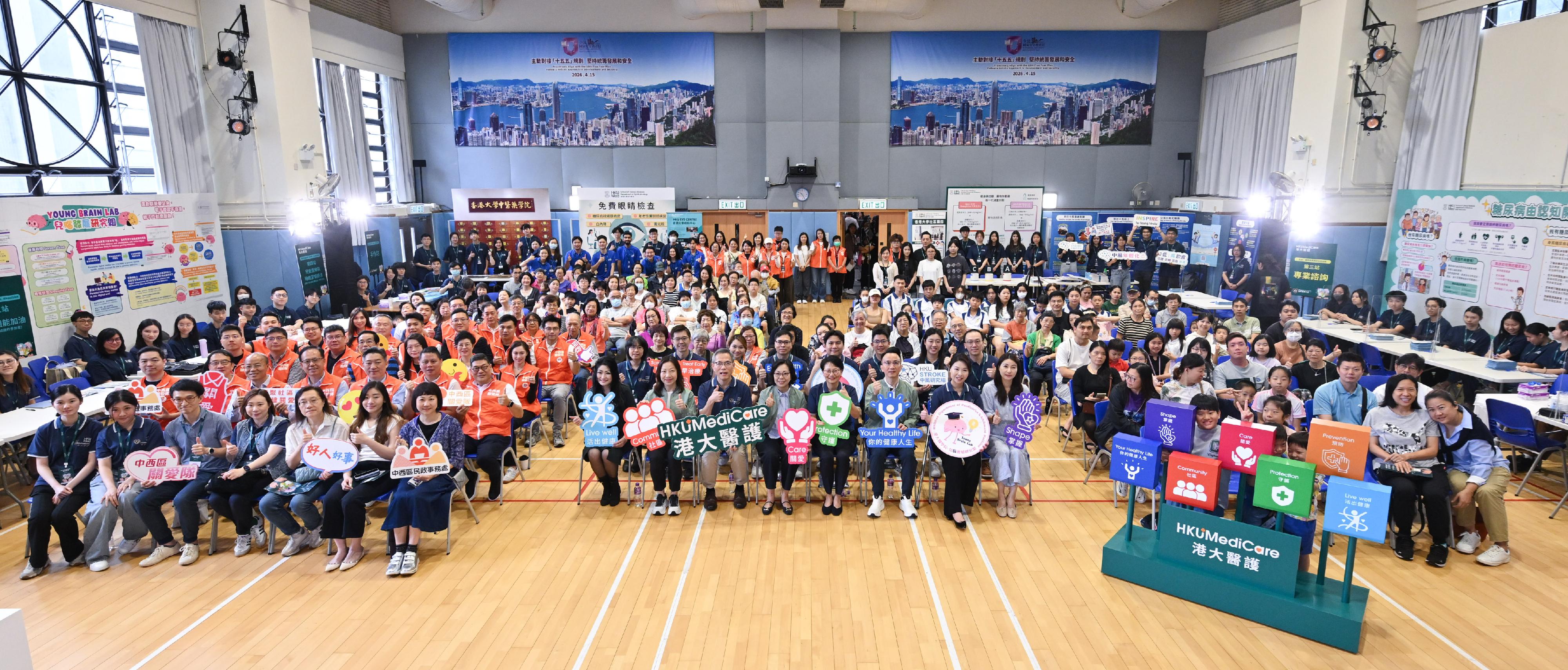 民政及青年事務局（民青局）、地區服務及關愛隊伍和香港大學李嘉誠醫學院（港大醫學院）今日（四月七日）在西營盤社區綜合大樓社區會堂合辦「世界健康日2026：掌握你的健康人生&mdash;&mdash;18區關愛健康巡禮」計劃啟動儀式及首場地區外展健康推廣活動。圖示（前排左九起）民政事務總署署長杜潔麗、港大醫學院院長劉澤星教授、民青局局長麥美娟、香港大學行政及財務副校長謝凌潔貞、民青局常任秘書長李百全和其他嘉賓與參加者合照。