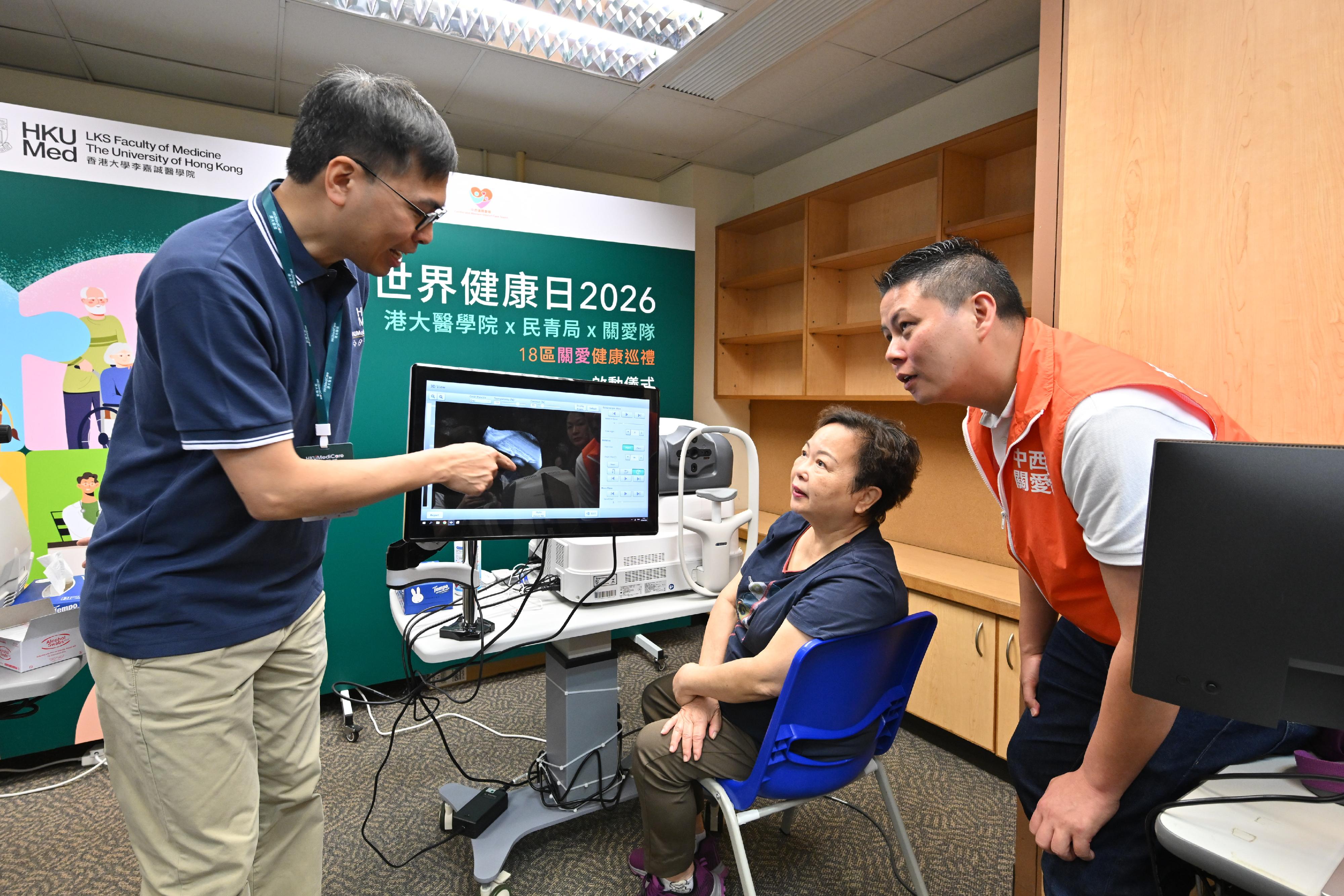 The Home and Youth Affairs Bureau, the District Services & Community Care Teams (Care Teams), and the Li Ka Shing Faculty of Medicine of the University of Hong Kong held the kick-off ceremony of the "Shape Your Healthy Life: 18 District Health Community Project" and the first district outreach health promotion event at the Sai Ying Pun Community Complex Community Hall today (April 7). Photo shows a member of the Care Teams accompanying a participant for an eye examination.