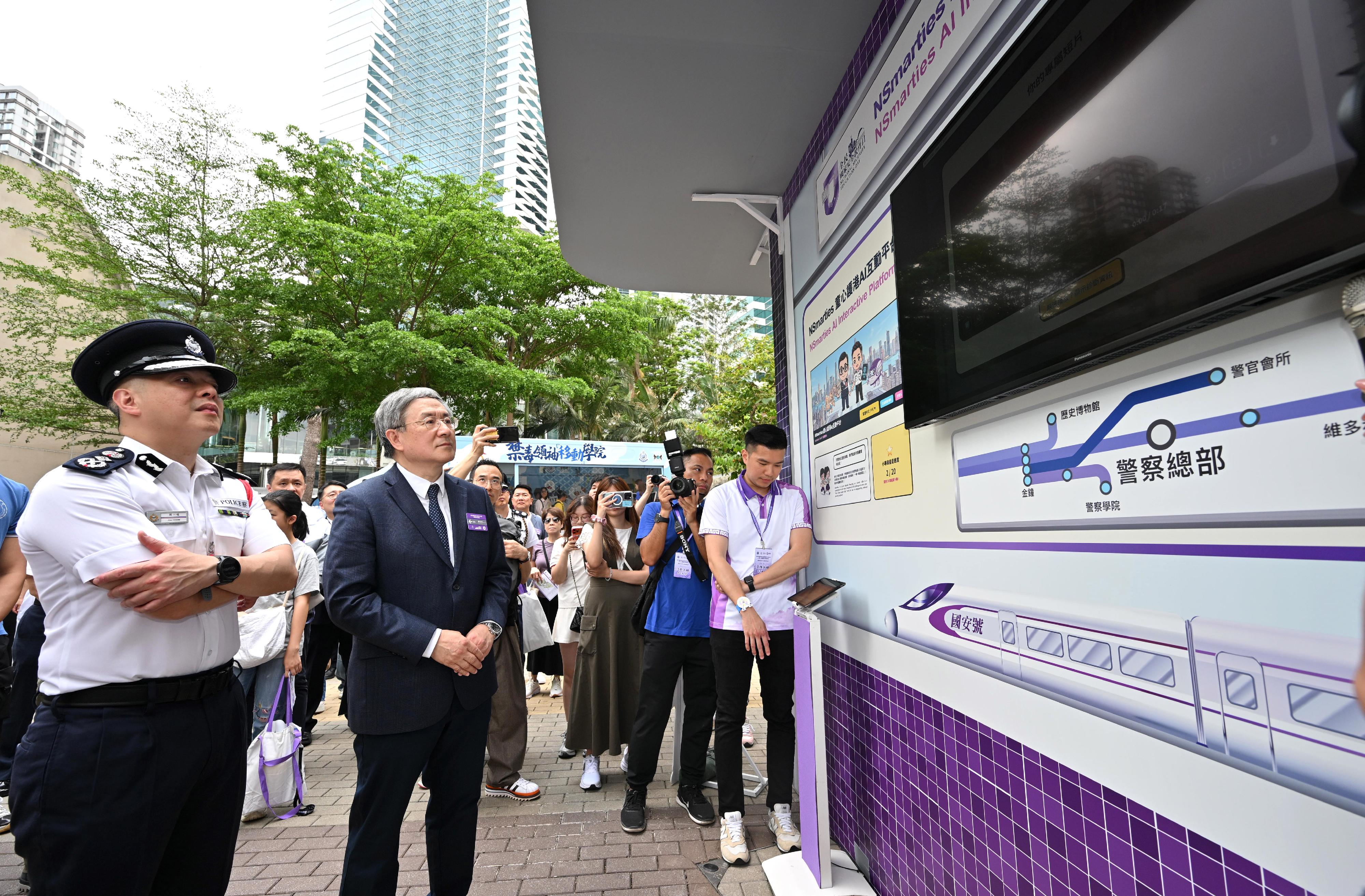 The Hong Kong Police Force held the National Security Education Day 2026 cum Hong Kong Police Force Fun Day today (April 12). The Deputy Chief Secretary for Administration, Mr Cheuk Wing-hing (second left), accompanied by the Commissioner of Police, Mr Chow Yat-ming (first left), visits the new &ldquo;NSmarties AI Interactive Platform&rdquo;.