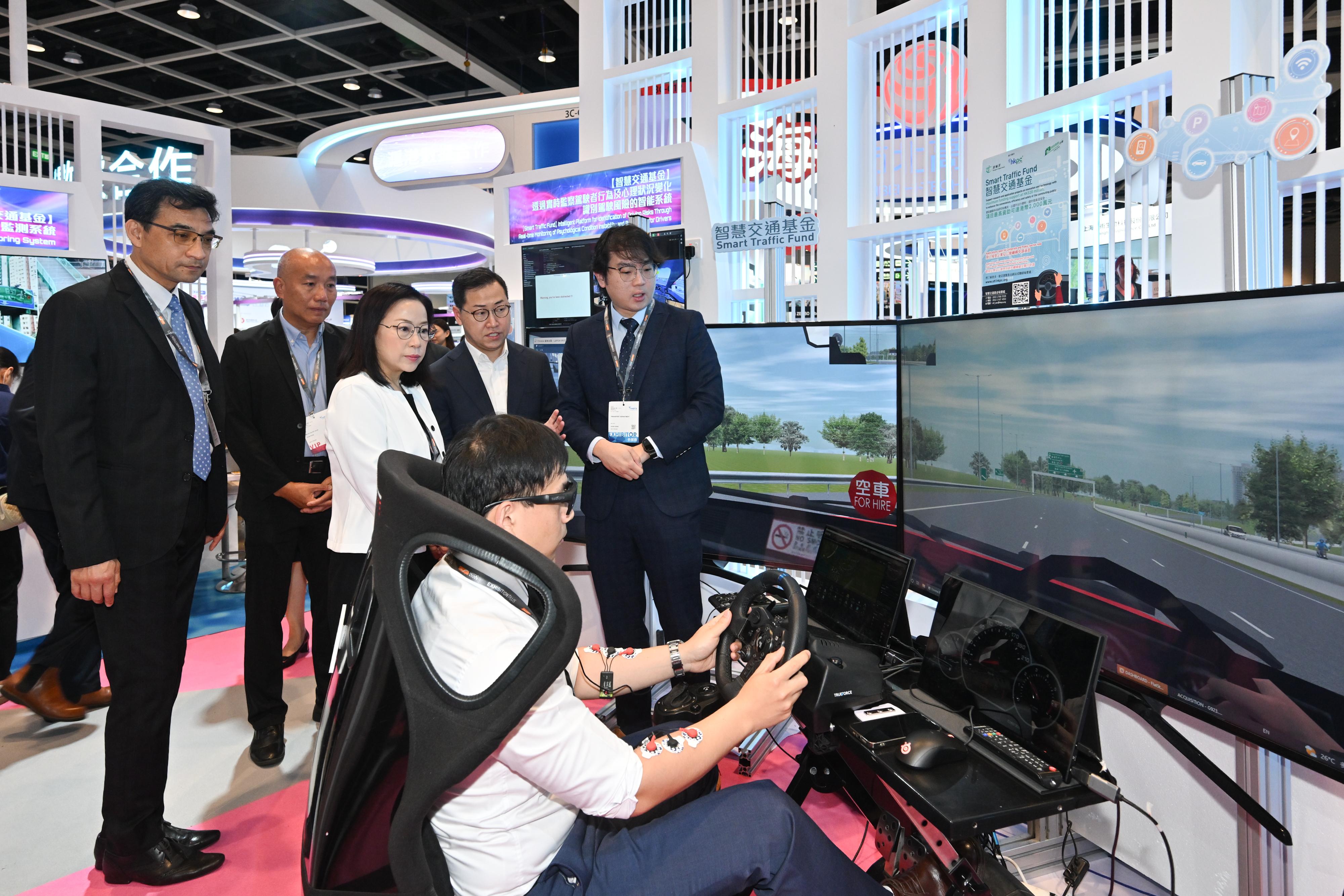 The Commissioner for Transport, Miss Winnie Tse, today (April 13) visited the InnoEX to learn more about the Smart Traffic Fund projects showcased at the Smart Hong Kong Pavilion, and experience the integration of digital technology and artificial intelligence into traffic and transport solutions. Photo shows Miss Tse (back row, centre) looking at an intelligent platform for identification of driving risks through real-time monitoring of psychological condition instabilities and behaviours of drivers.