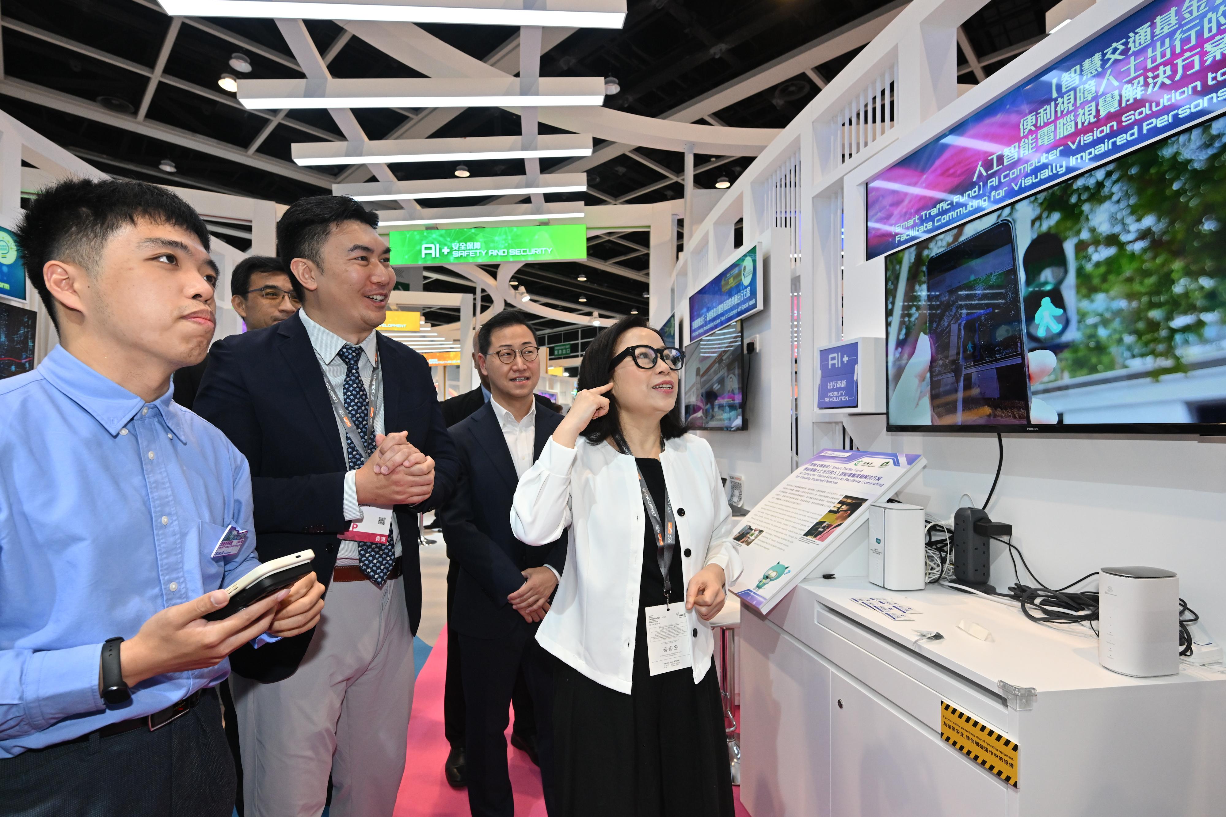 The Commissioner for Transport, Miss Winnie Tse, today (April 13) visited the InnoEX to learn more about the Smart Traffic Fund projects showcased at the Smart Hong Kong Pavilion, and experience the integration of digital technology and artificial intelligence into traffic and transport solutions. Photo shows Miss Tse (first right) wearing smart glasses which assist persons with visual impairment in identifying obstacles, bus stops and bus routes.&nbsp;