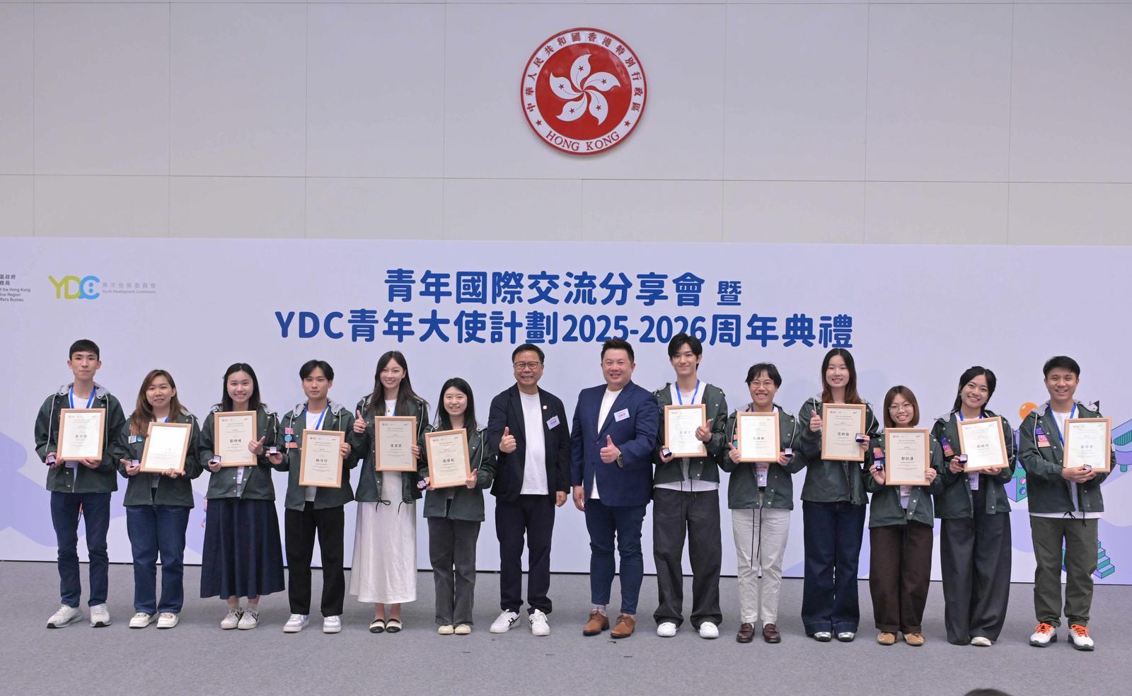 青年國際交流分享會暨YDC青年大使計劃2025-2026周年典禮今日（四月十八日）舉行。圖示青年專員陳瑞緯（左七）與青年發展委員會副主席梁毓偉（右七）向YDC青年大使頒發證書及義工服務嘉許狀。